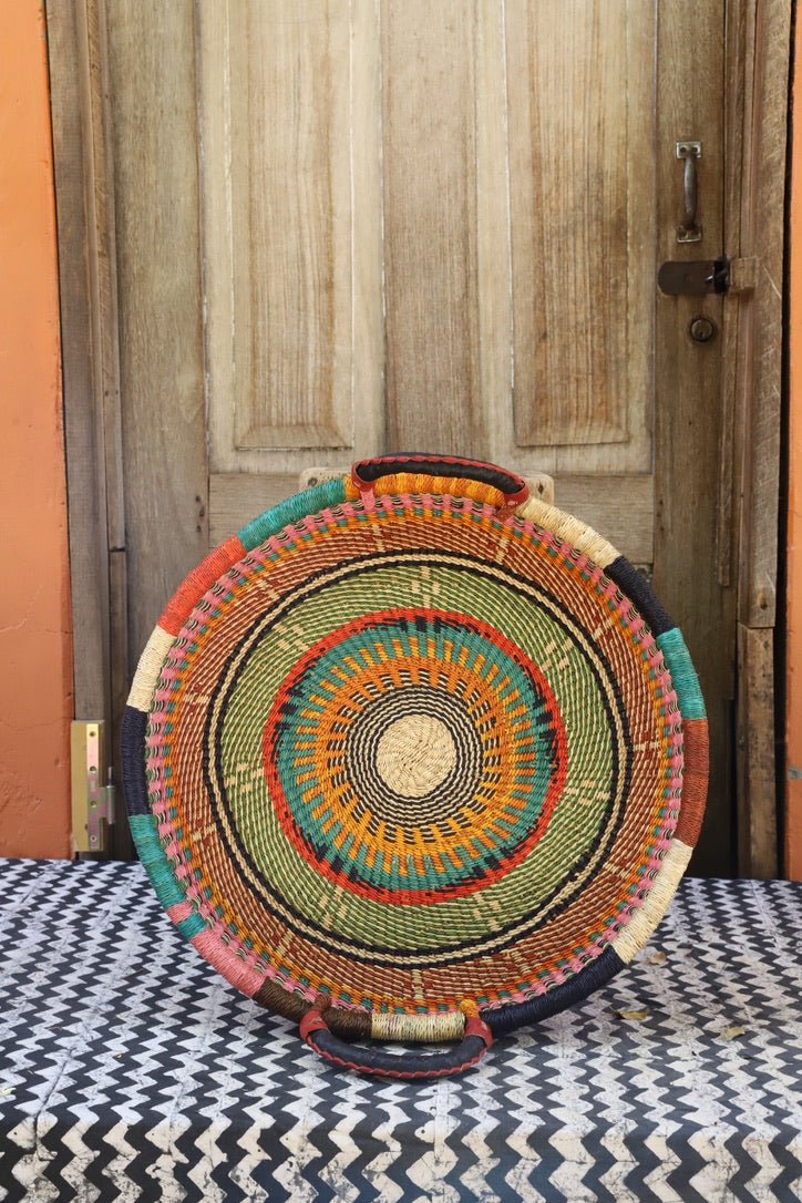 Woven basket with colourful patterns on black and white cloth in front of a wooden door