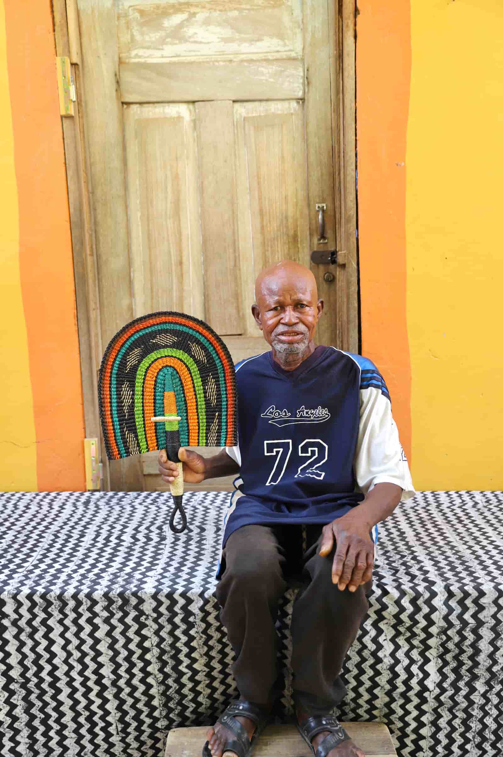 Man sitting on a black and white with a colorful wall and wooden door in the background