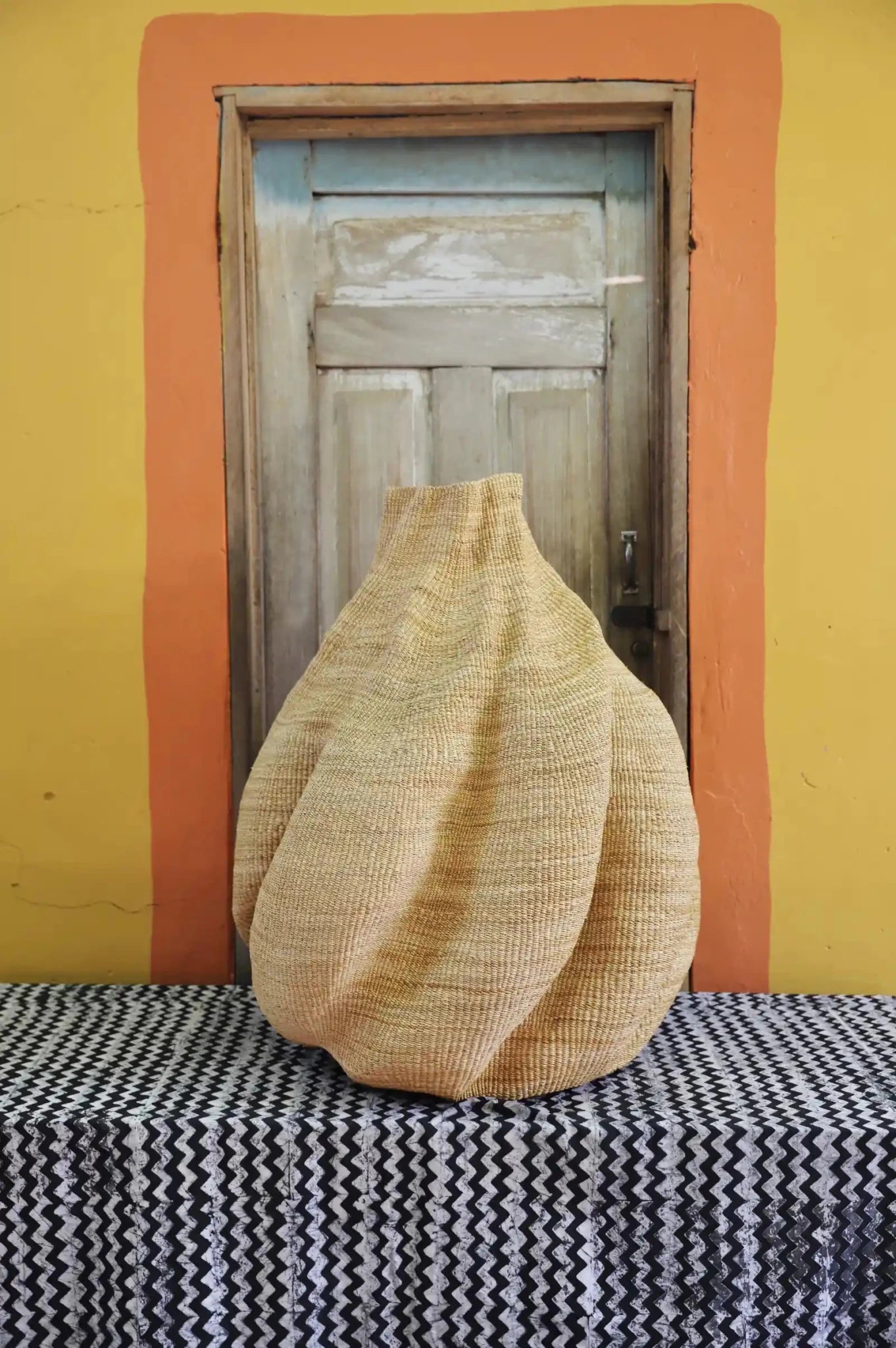 Decorative basket  on a black and white cloth against a wooden door.