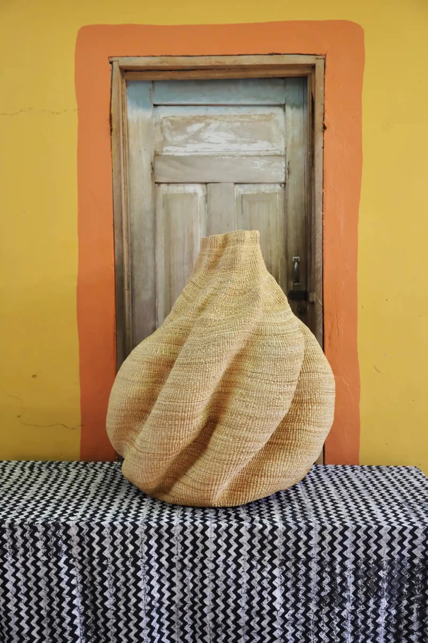 Decorative basket  on a black and white cloth against a wooden door.