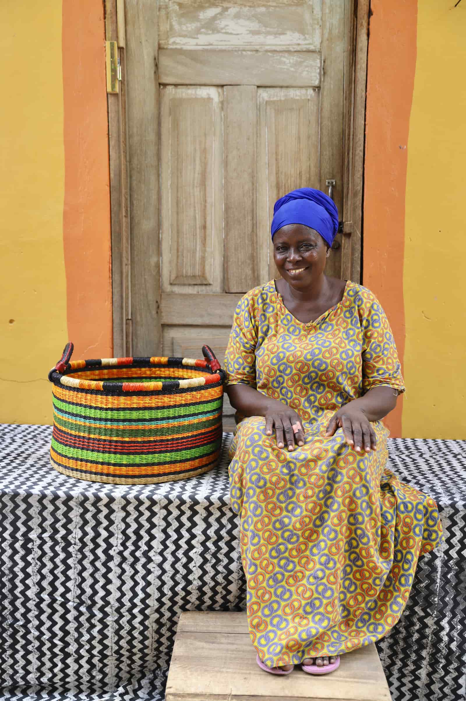 Woven Tub (Medium) with man weaver handwoven in Ghana sitting on black and white cloth and wooden door in background