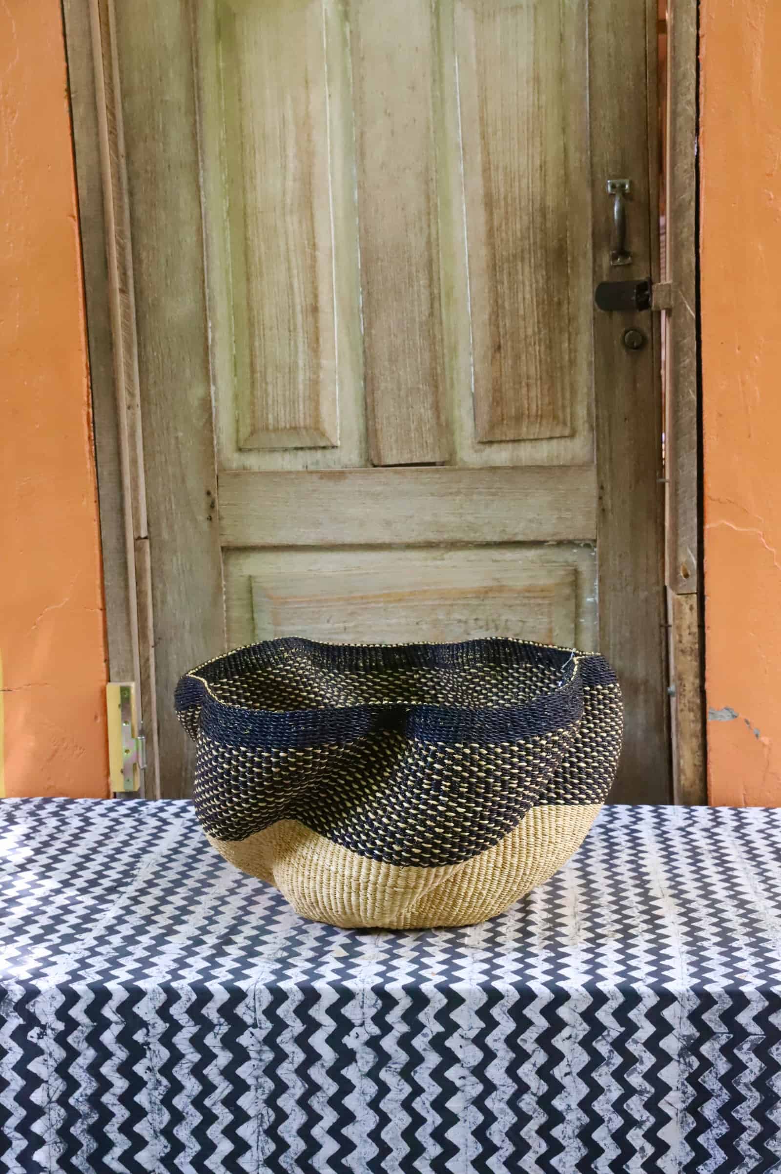 Decorative woven basket  on a black and white cloth against a wooden door.
