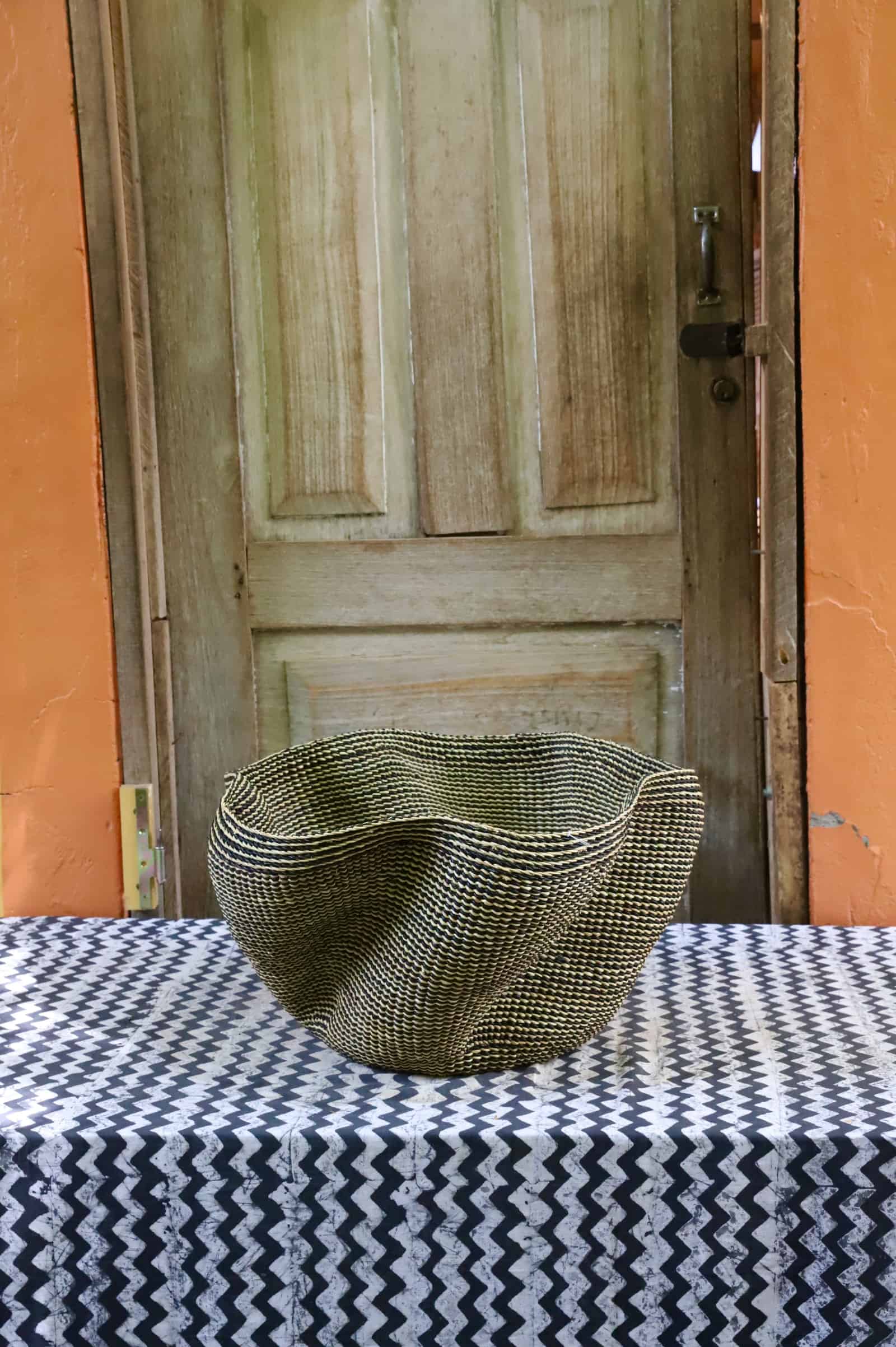 Decorative woven basket  on a black and white cloth against a wooden door.