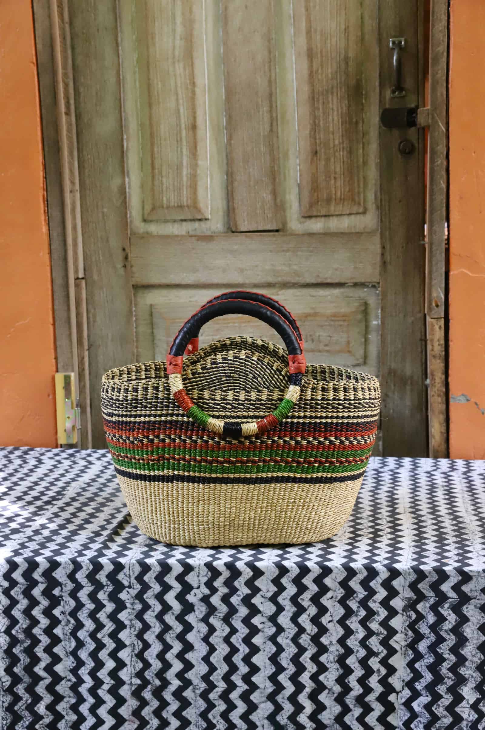 Colorful woven carry on bag on a black and white cloth against a wooden door.