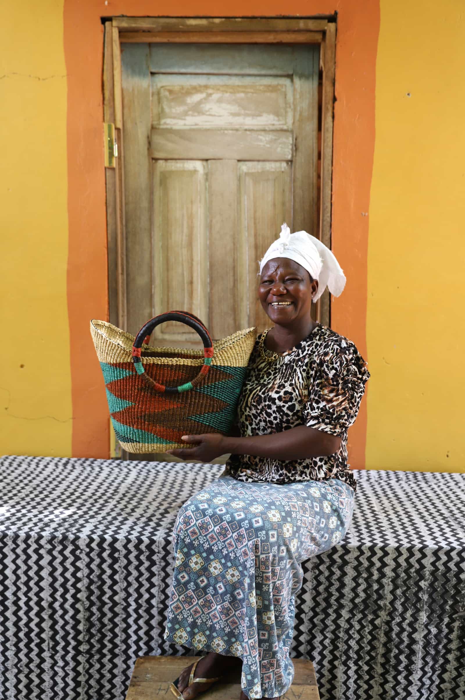 Woman in leopard print top holding a woven beach bag in natural straw with teal chevron pattern