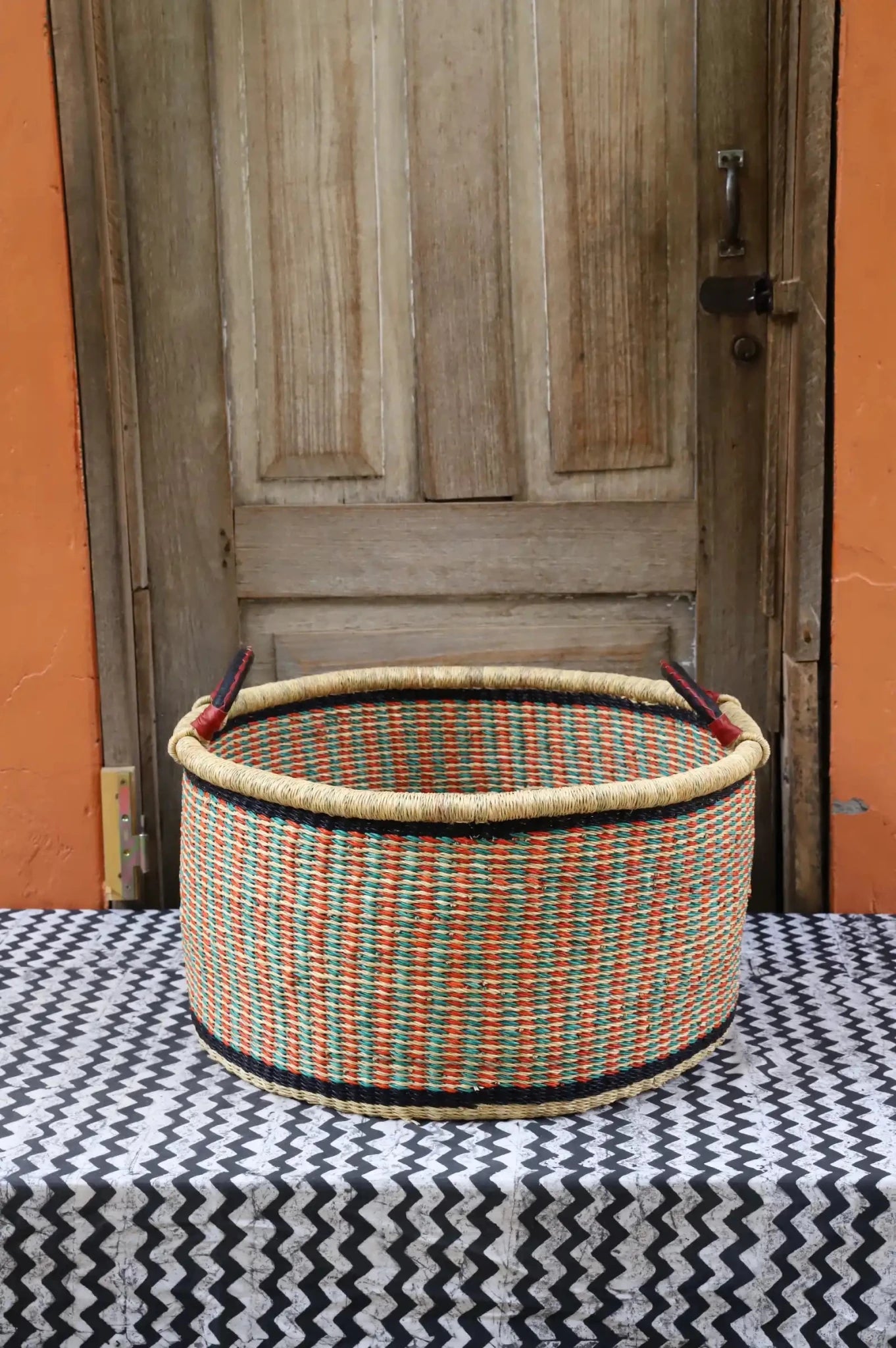 Woven Tub (Large) handwoven in Ghana sitting on black and white cloth with wooden door background