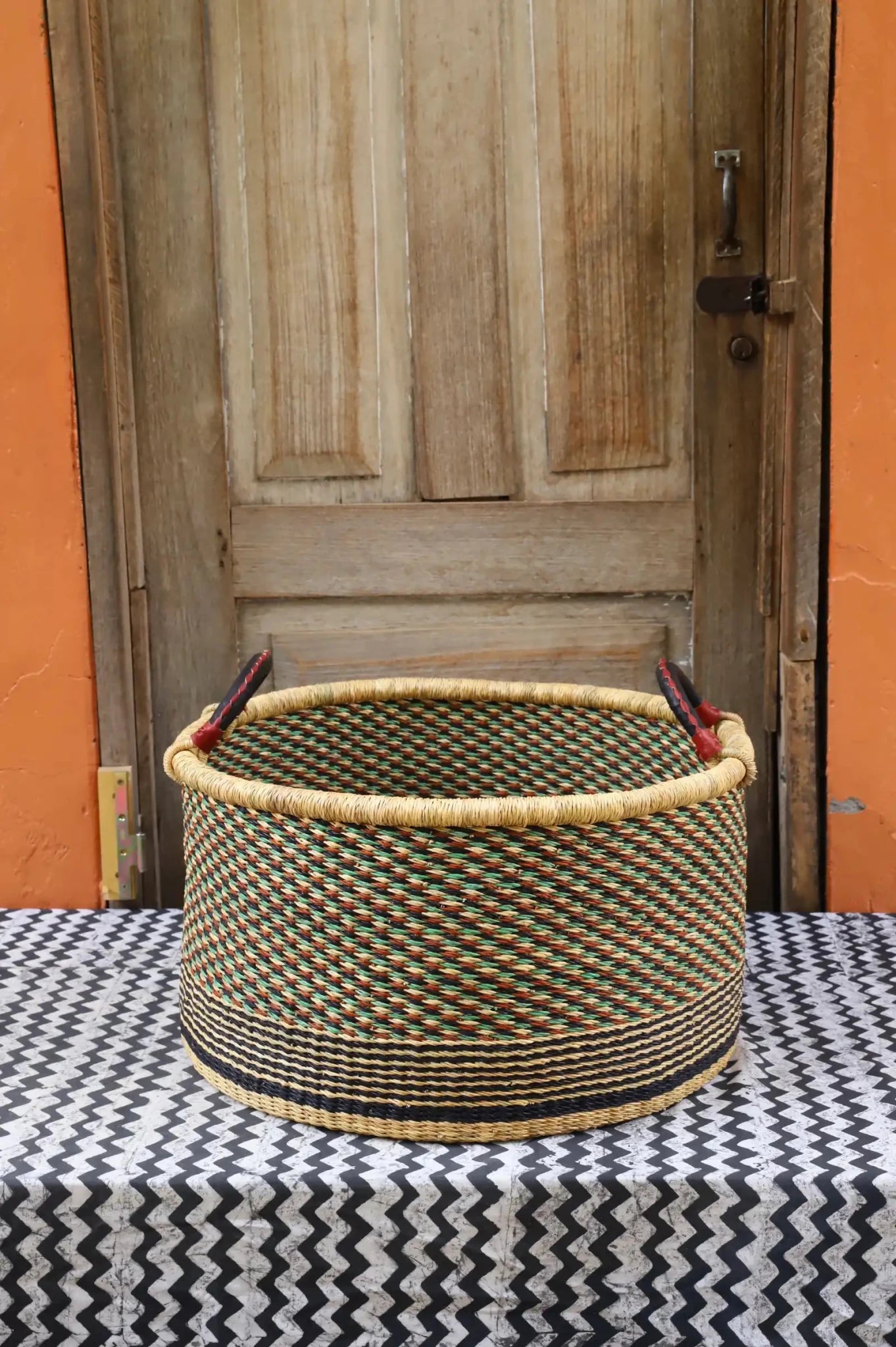 Woven Tub (Large) handwoven in Ghana sitting on black and white cloth with wooden door background


