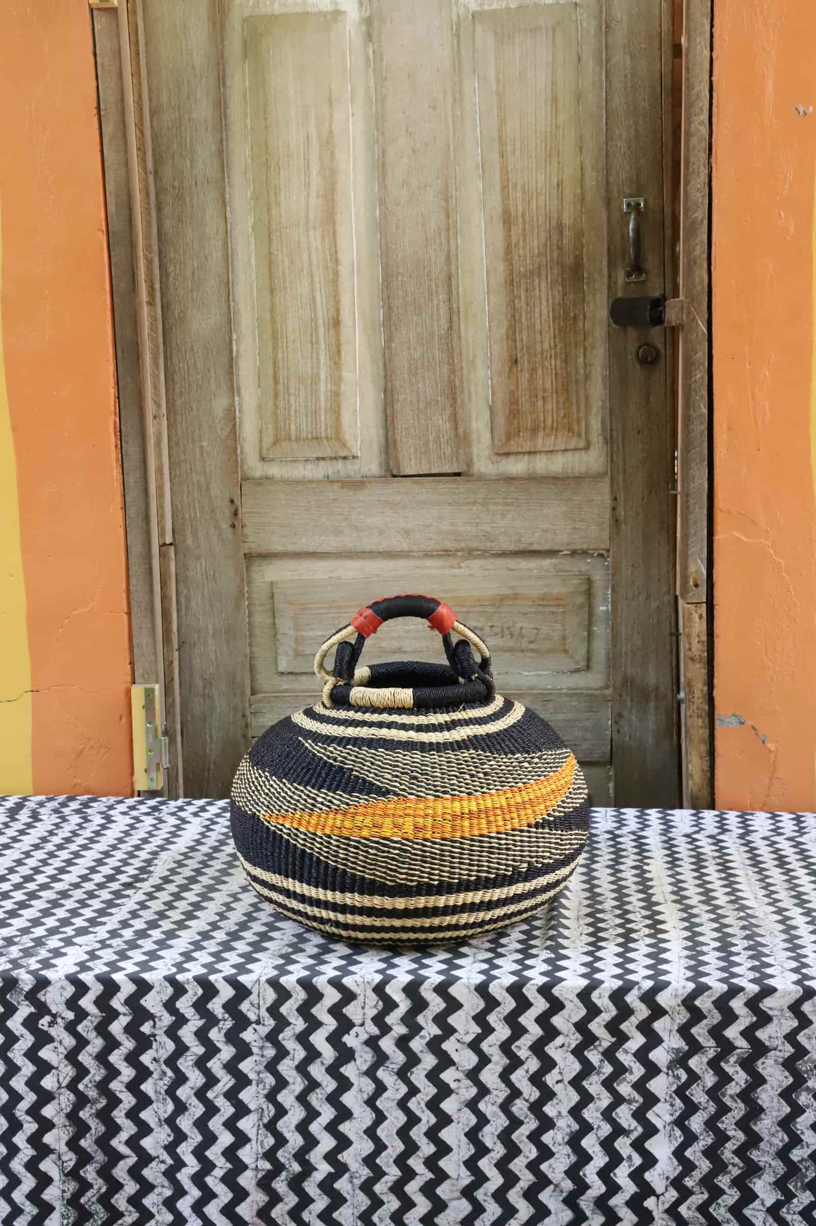 Large pot storage basket in black and natural straw with amber diagonal stripe, red leather handle