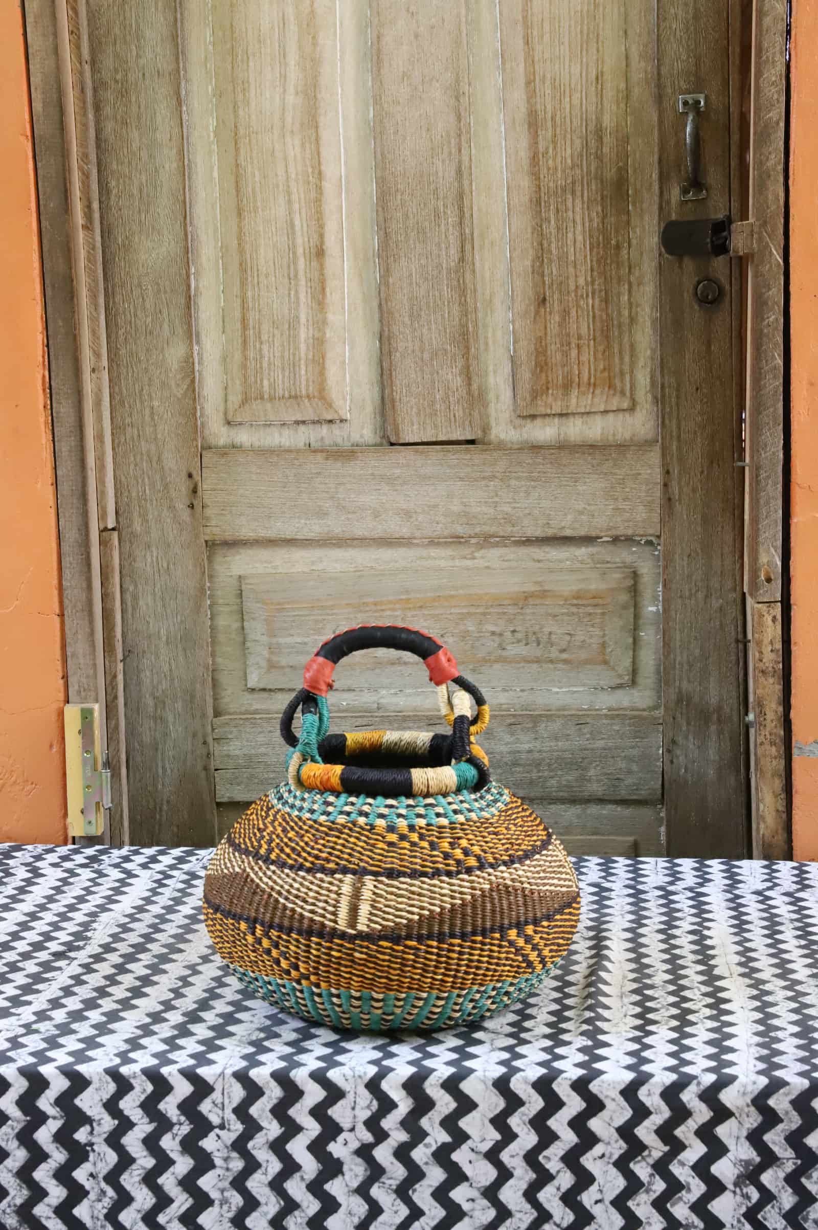 Small pot storage basket with teal, amber and black geometric pattern, leather-wrapped handle