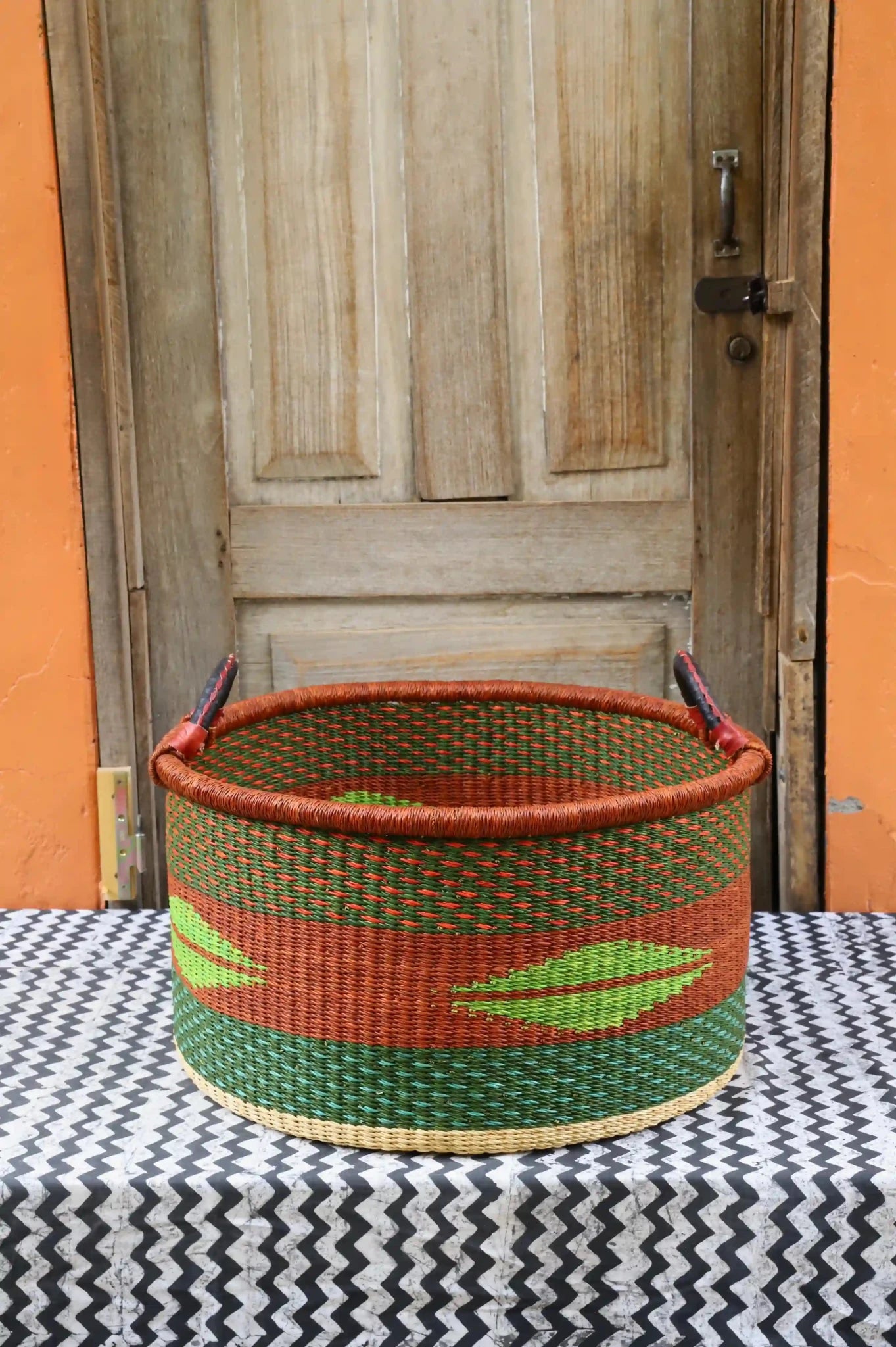 Woven Tub (Large) handwoven in Ghana sitting on black and white cloth with wooden door background

