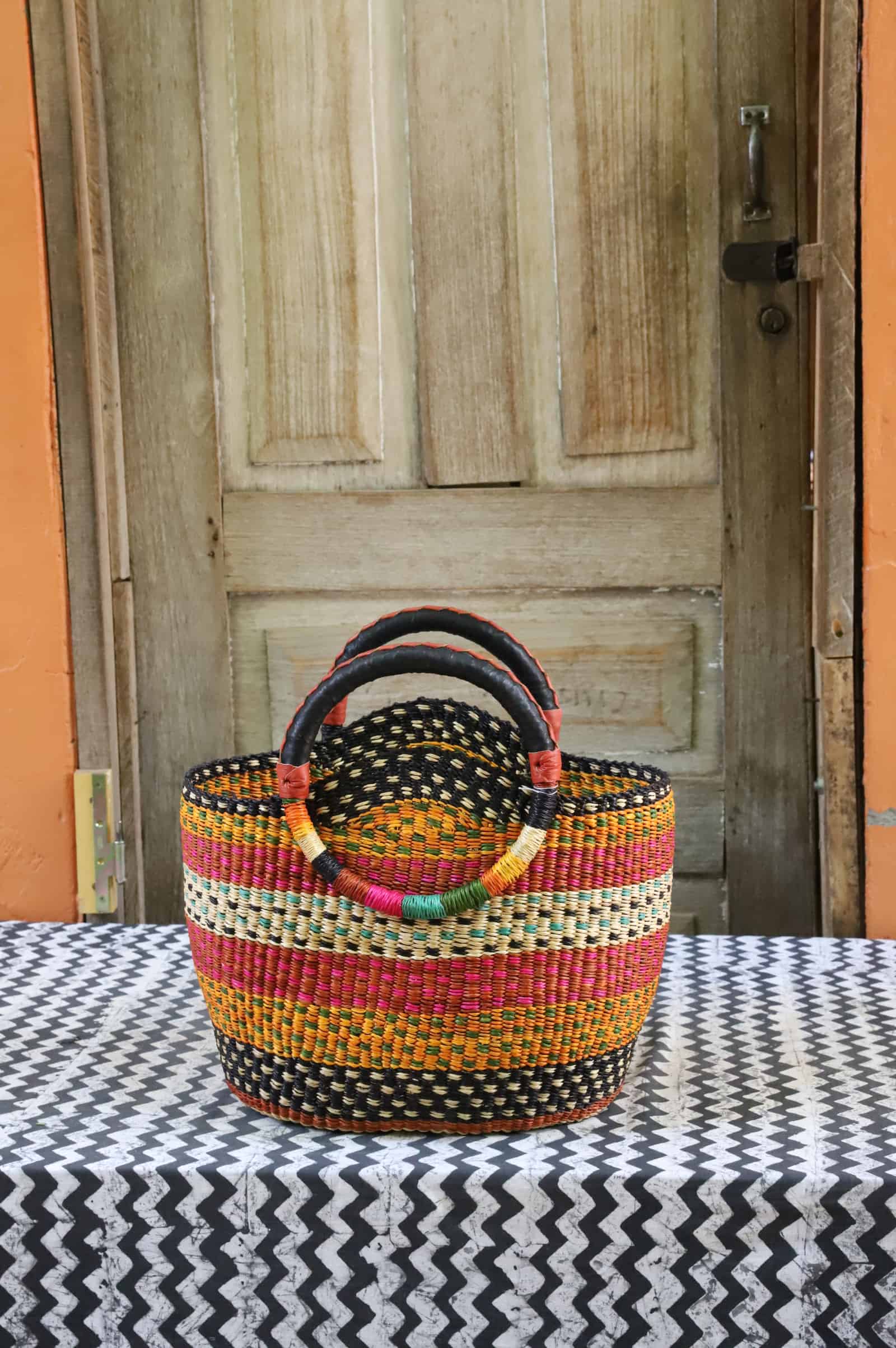 Colorful woven carry on bag on a black and white cloth against a wooden door.