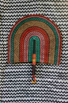 Naba Penga wall décor: teal, terracotta and pink rainbow arch, flat lay on chevron fabric