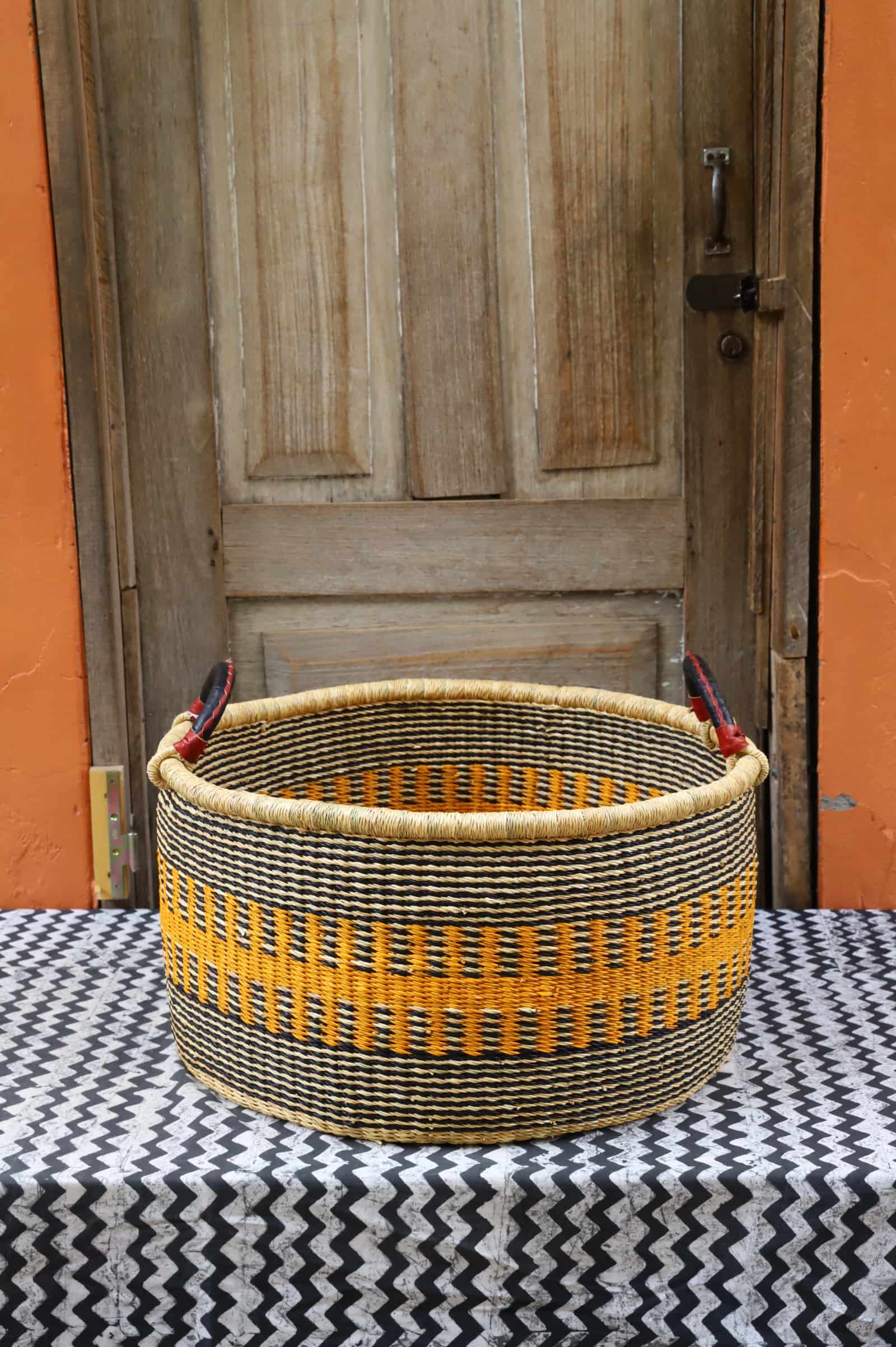 Woven Tub (Large) handwoven in Ghana sitting on black and white cloth with wooden door background