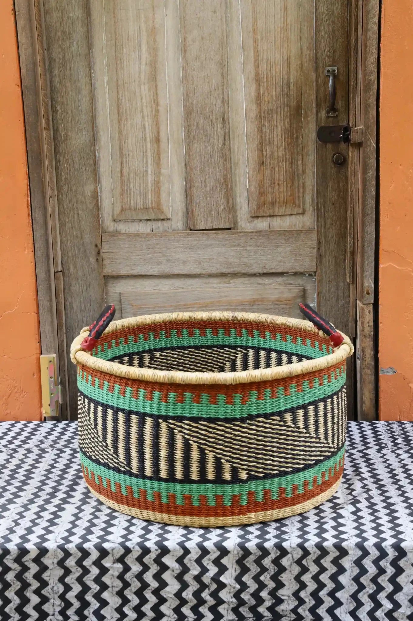 Woven Tub (Large) handwoven in Ghana sitting on black and white cloth with wooden door background
