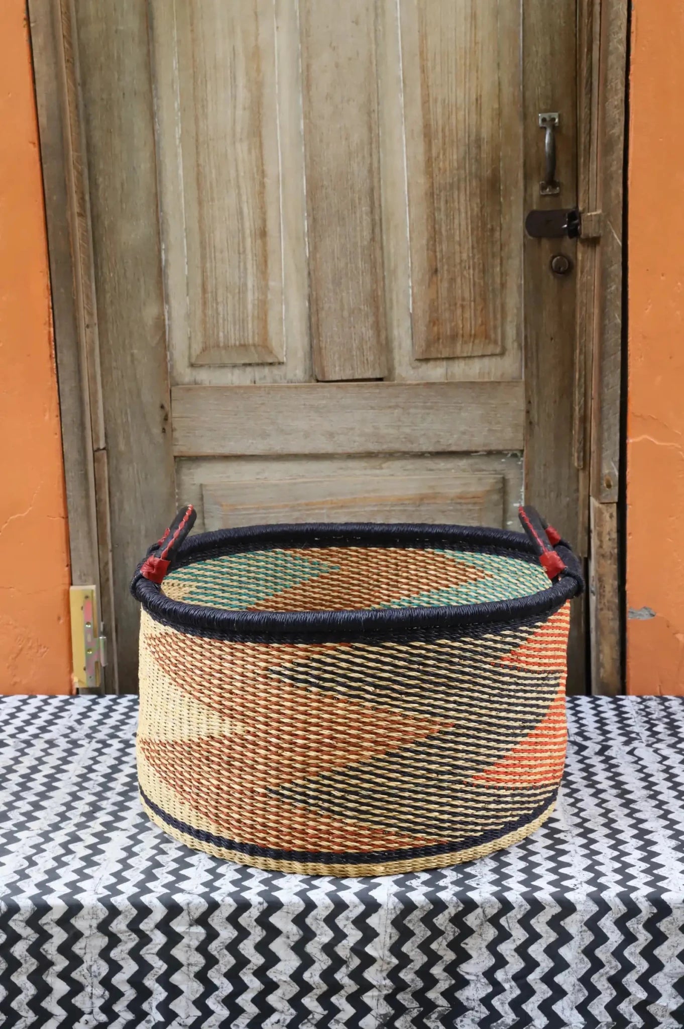 Woven Tub (Large) handwoven in Ghana sitting on black and white cloth with wooden door background

