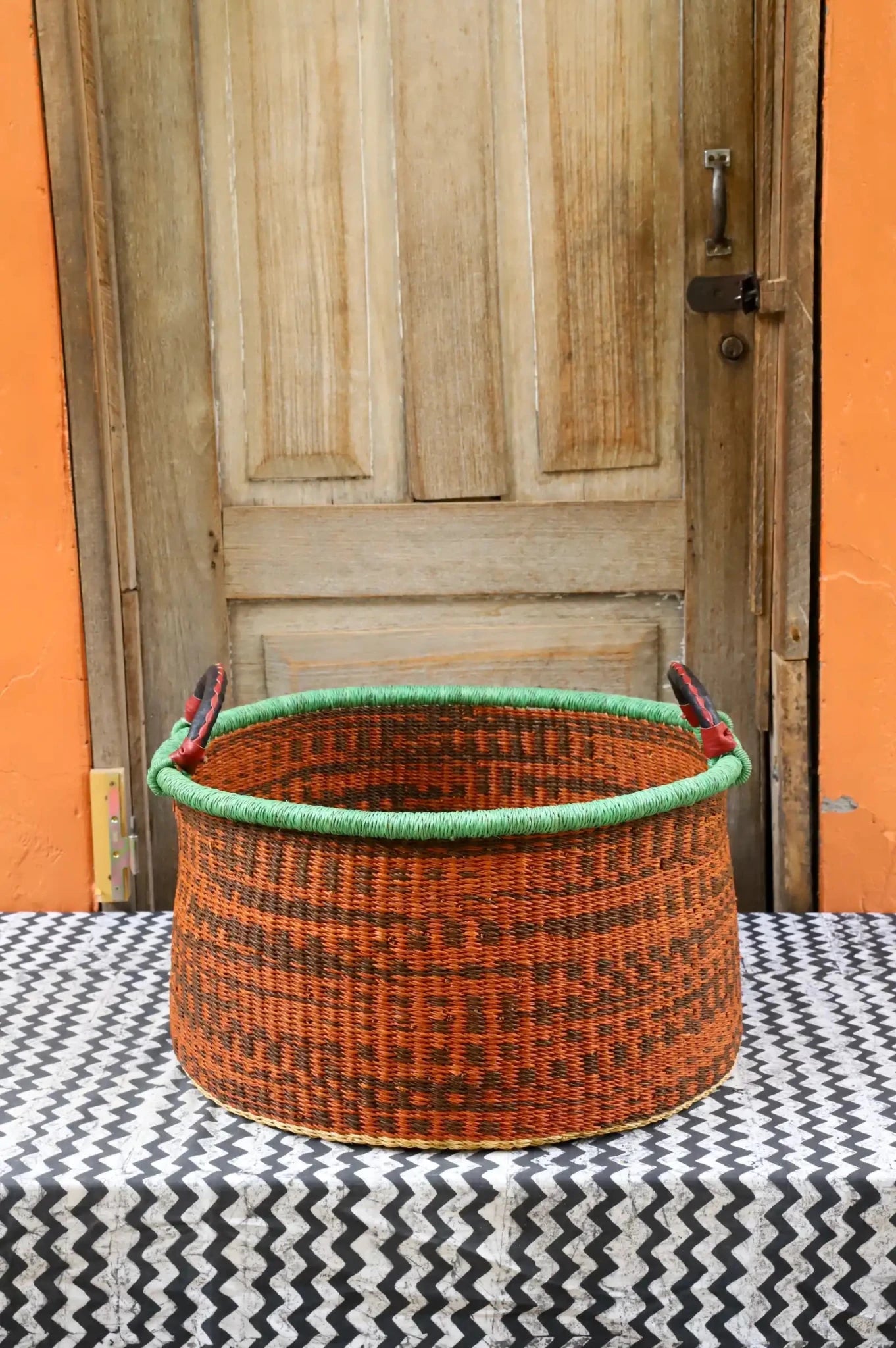 Woven Tub (Large) handwoven in Ghana sitting on black and white cloth with wooden door background

