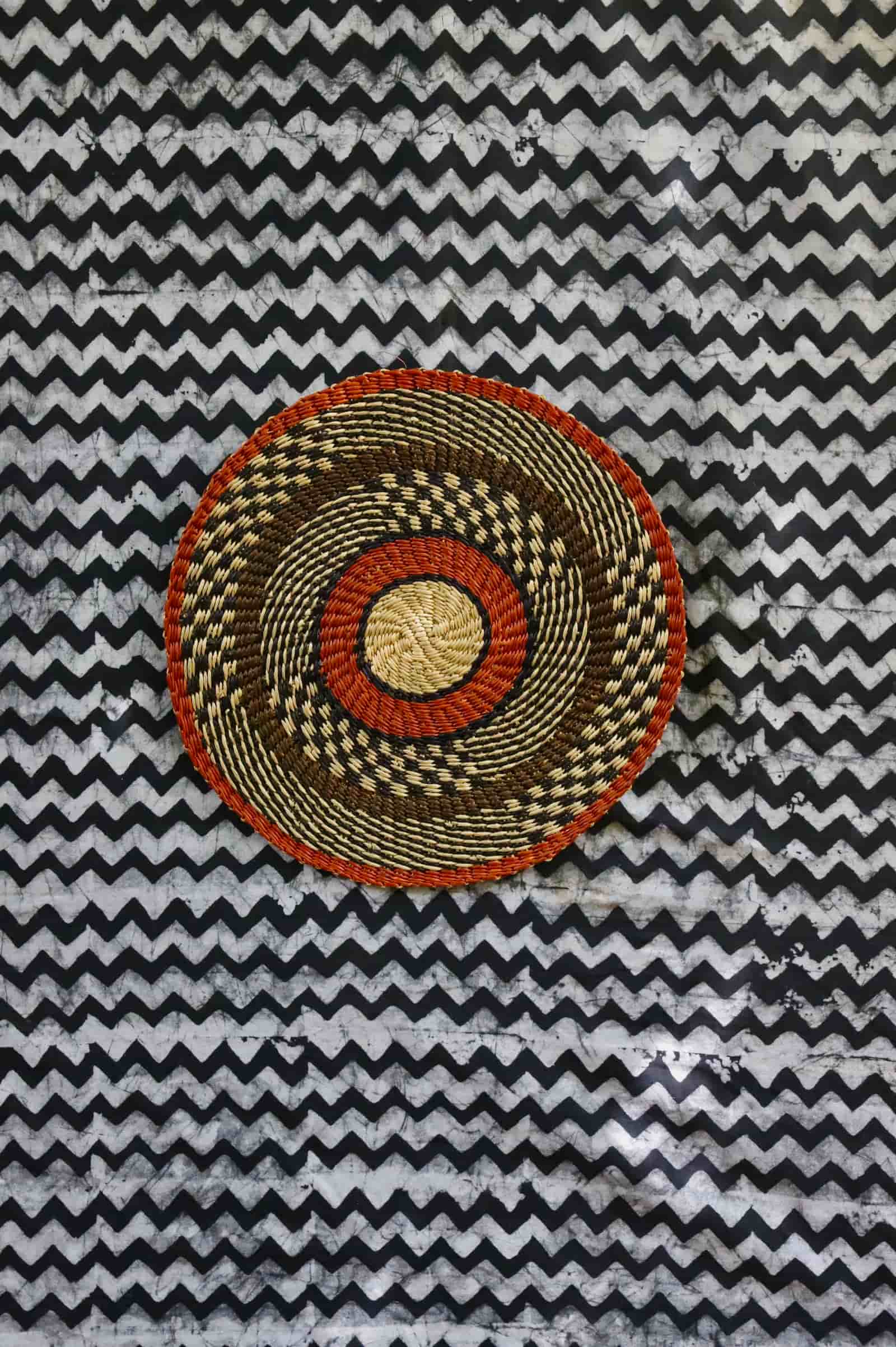 Large woven placemat with terracotta outer rim, black and natural checkered mid-band