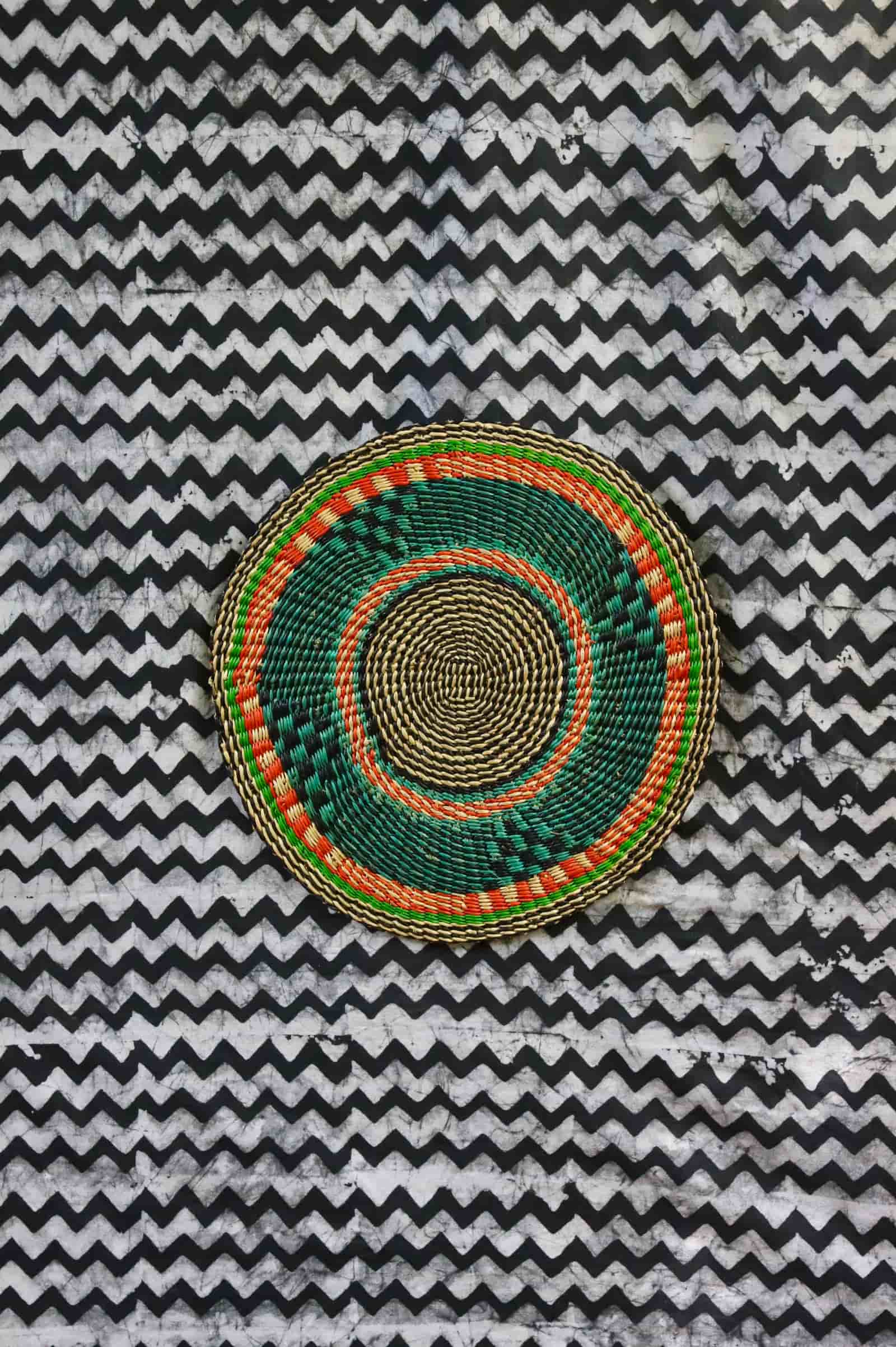 Large woven placemat in forest green with orange accent ring and natural straw border