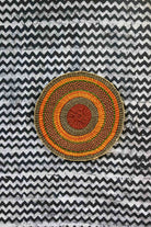 Large woven placemat with terracotta, orange, green and olive concentric bands