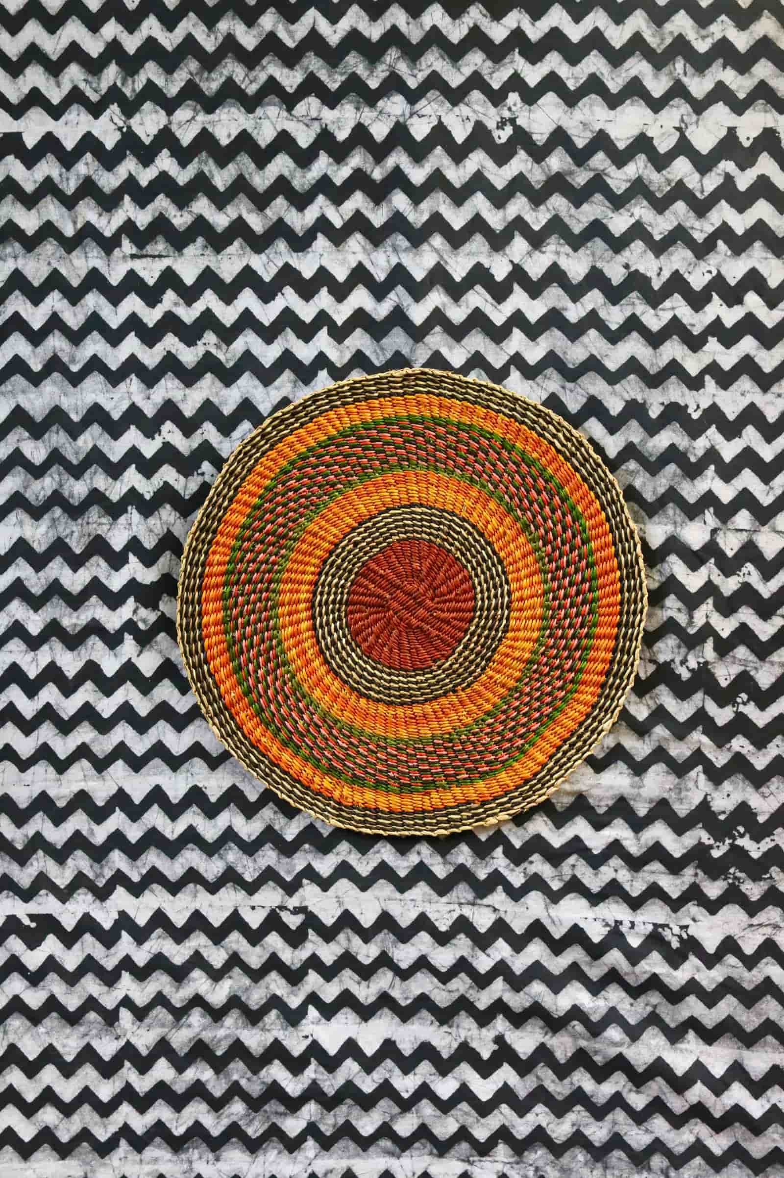 Large woven placemat with terracotta, orange, green and olive concentric bands