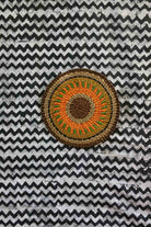 Small woven placemat with orange and green starburst pattern, dark border
