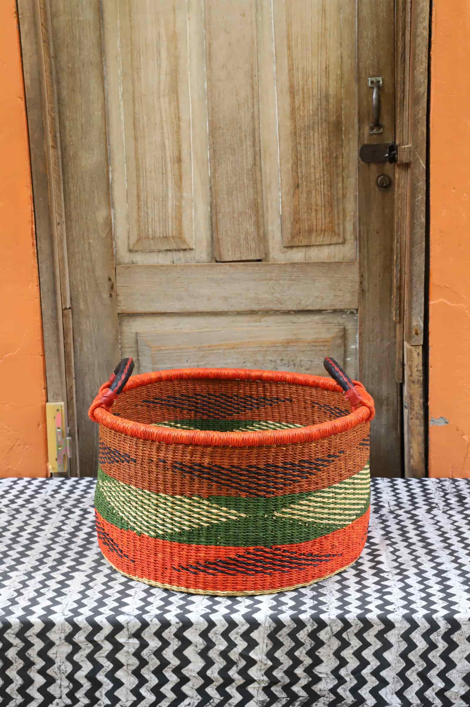 Woven Tub (Medium) handwoven in Ghana sitting on black and white cloth with wooden door background