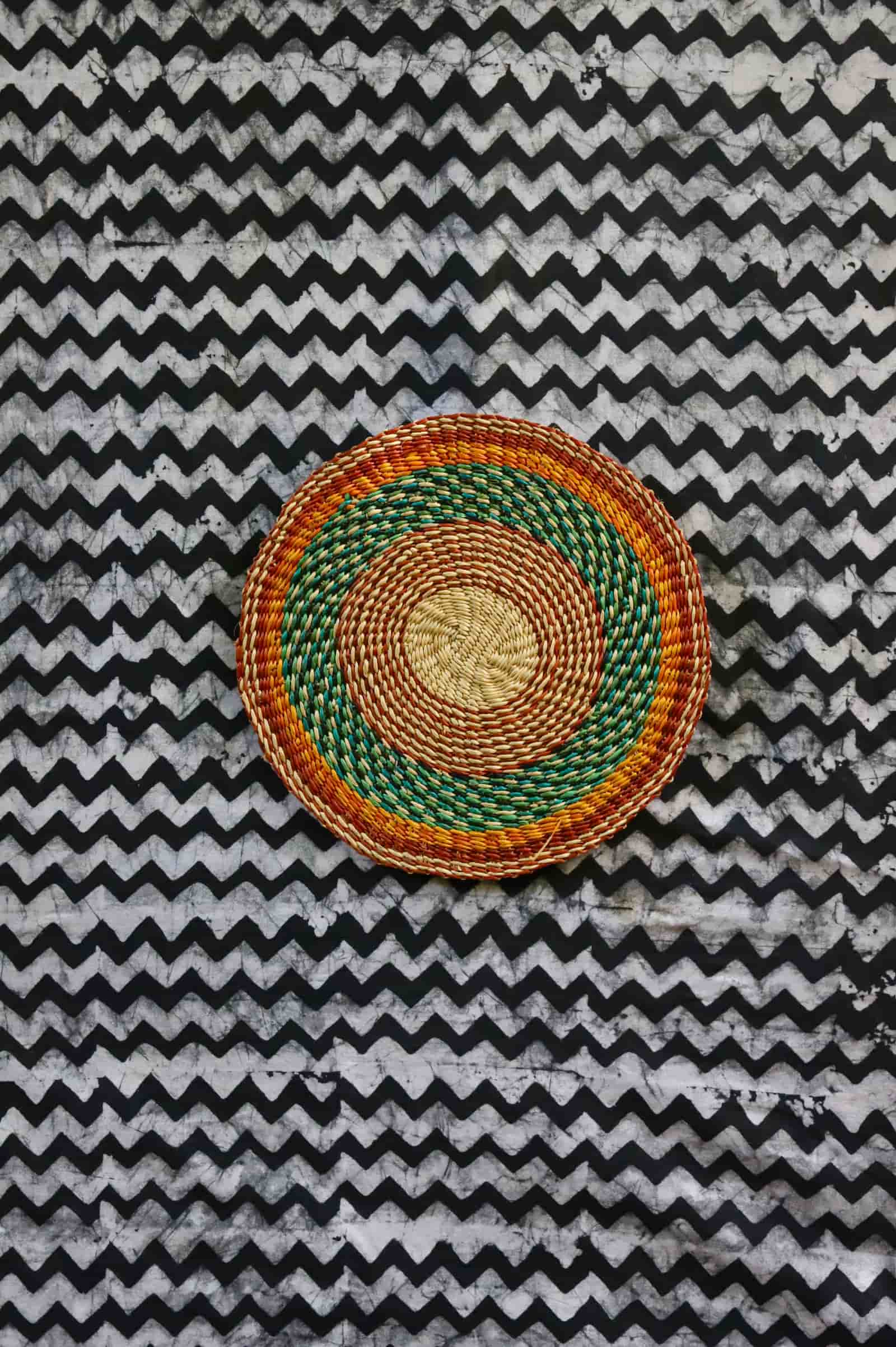 Small woven placemat set of 4 — green and orange concentric rings on natural straw