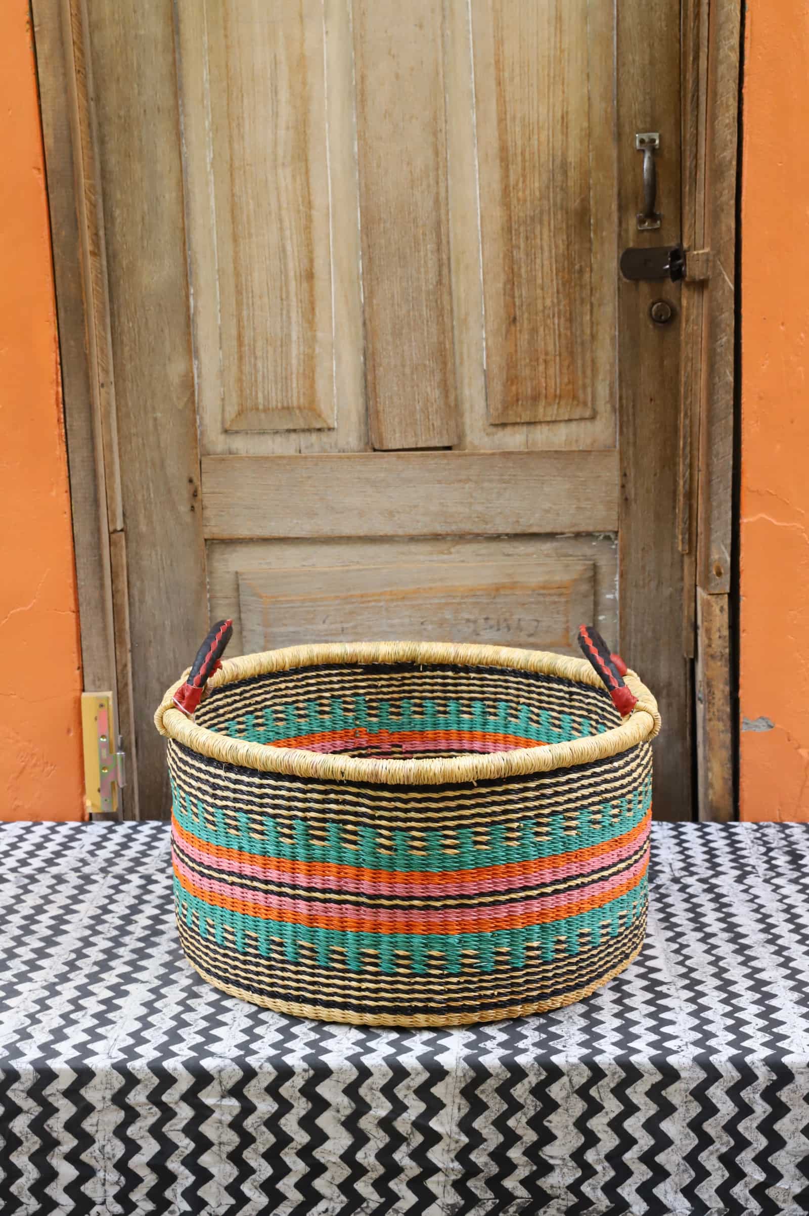 Woven Tub (Medium) handwoven in Ghana sitting on black and white cloth with wooden door background

