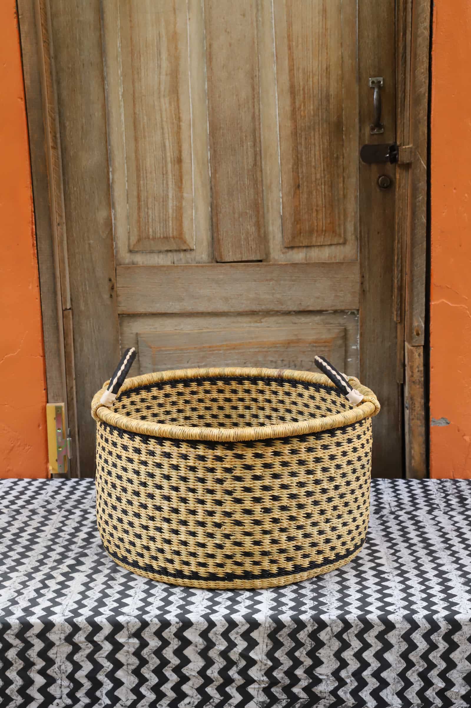 Woven Tub (Medium) handwoven in Ghana sitting on black and white cloth with wooden door background