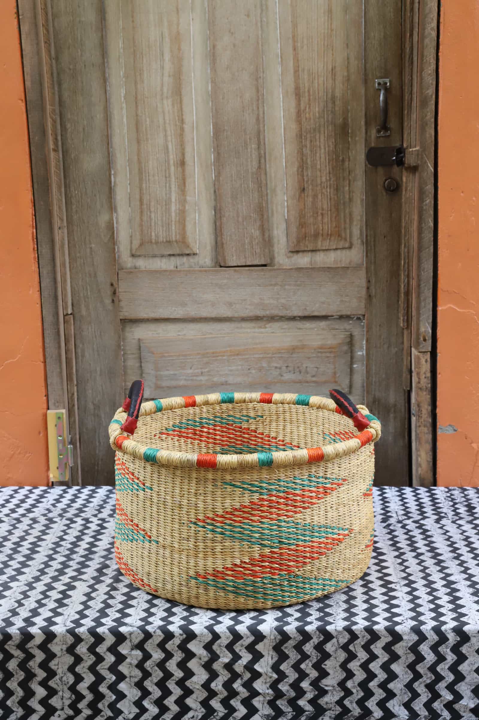 Woven Tub (Small) handwoven in Ghana sitting on black and white cloth with wooden door background

