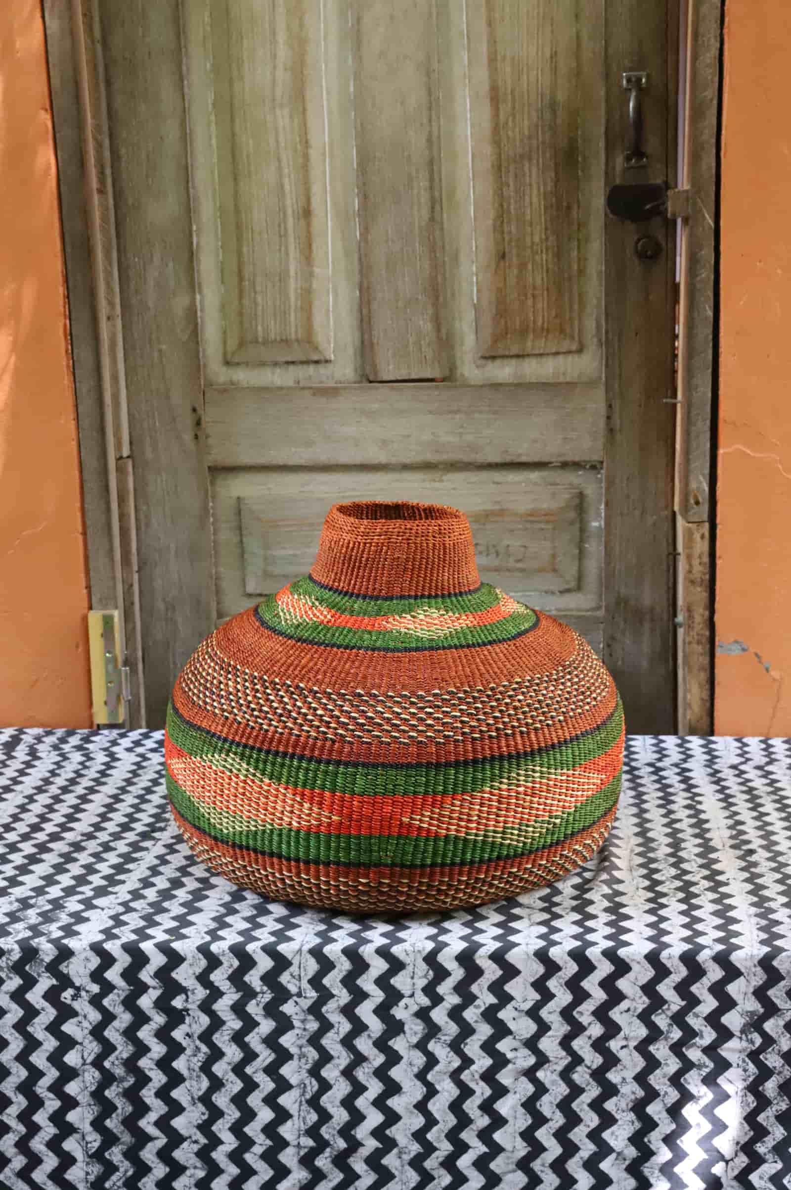 Nosere-Yure art basket: globe-shaped vessel with rust and green stripe bands, front view