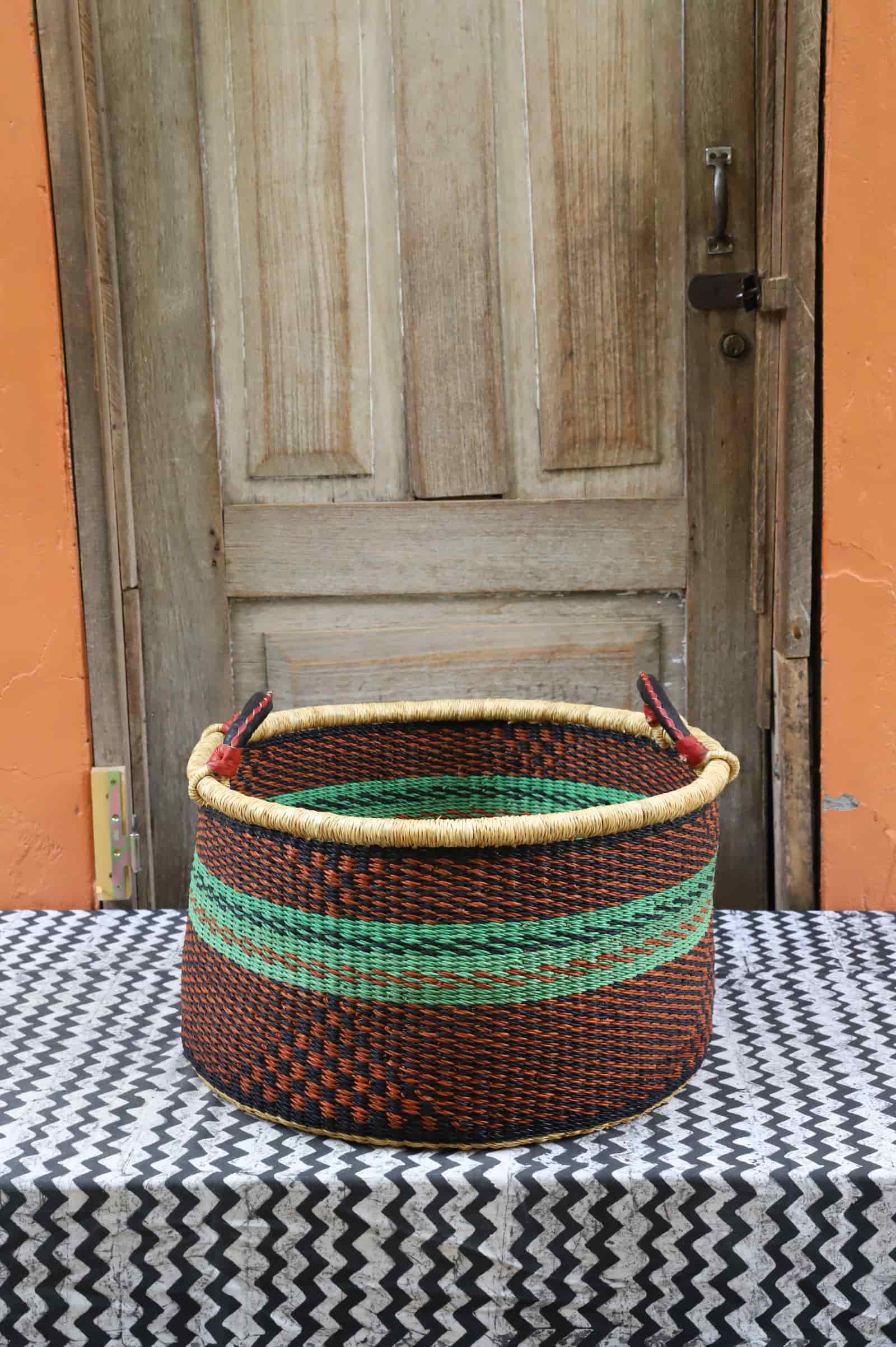 Woven Tub (Medium) handwoven in Ghana sitting on black and white cloth with wooden door background
