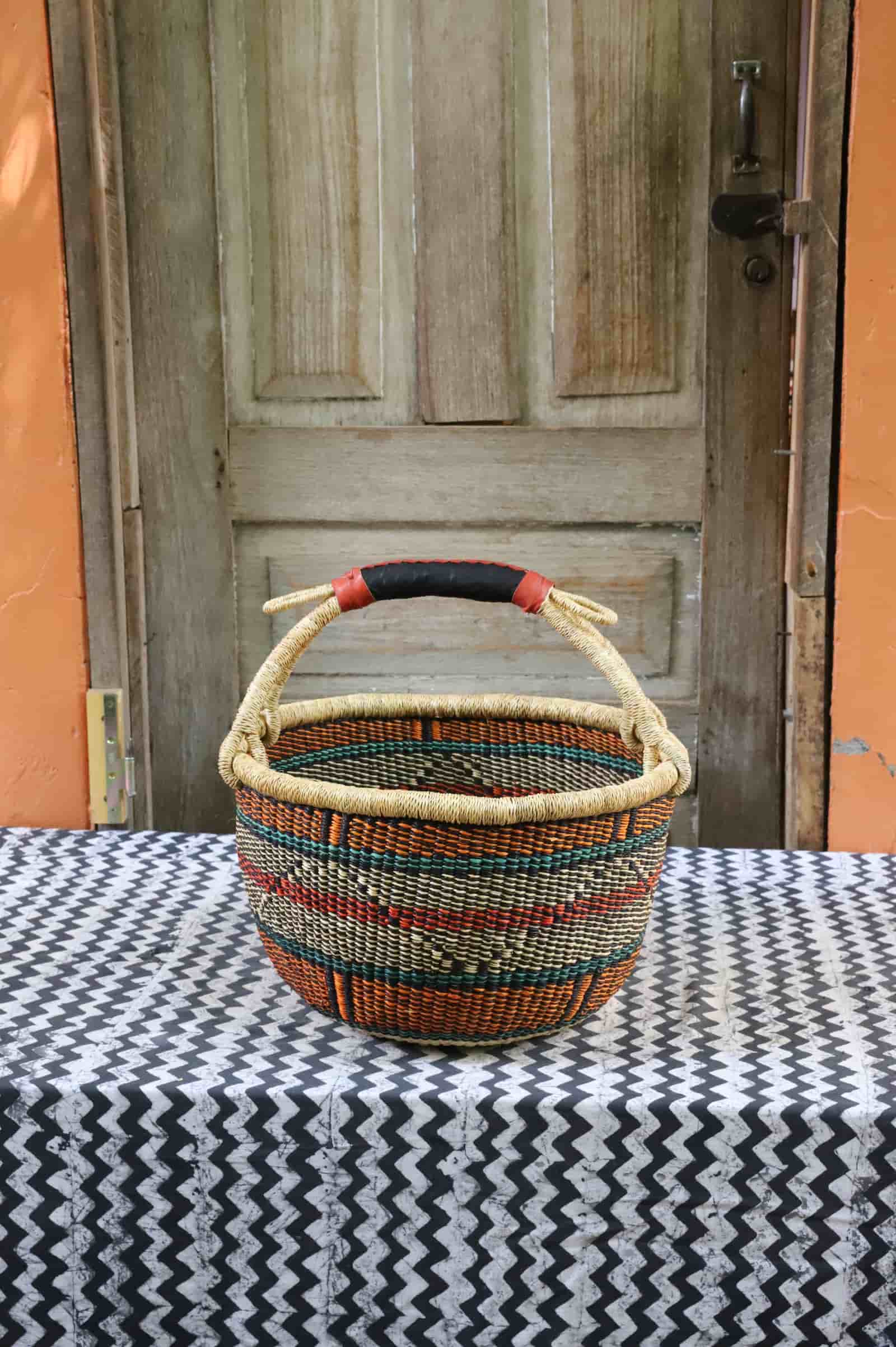 Large round Bolga basket in teal, red, orange and natural diamond pattern with a leather handle