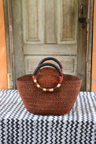 Naughty George weekend bag in deep rust with dark leather handles and gold banding