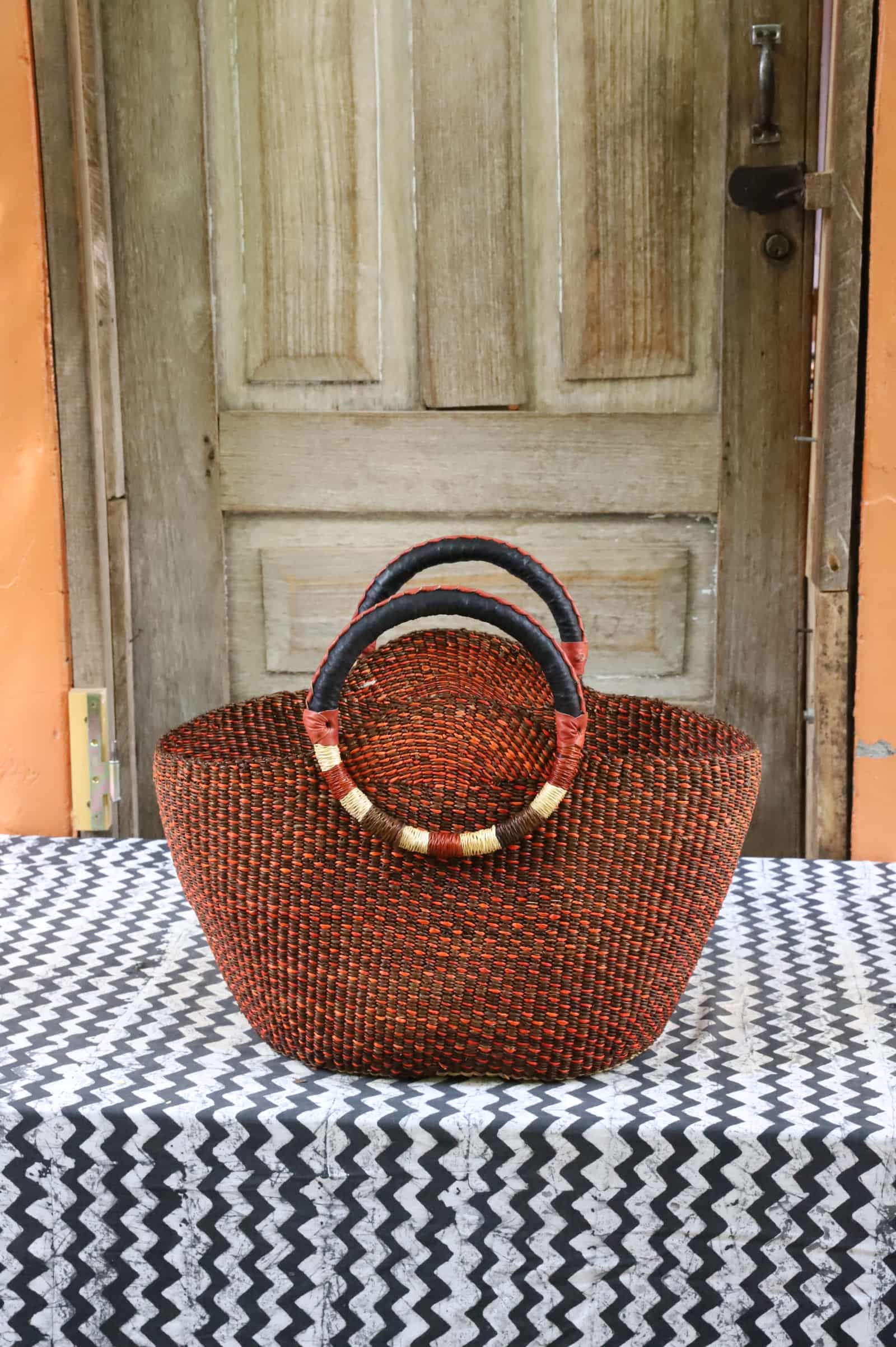 Naughty George weekend bag in deep rust with dark leather handles and gold banding