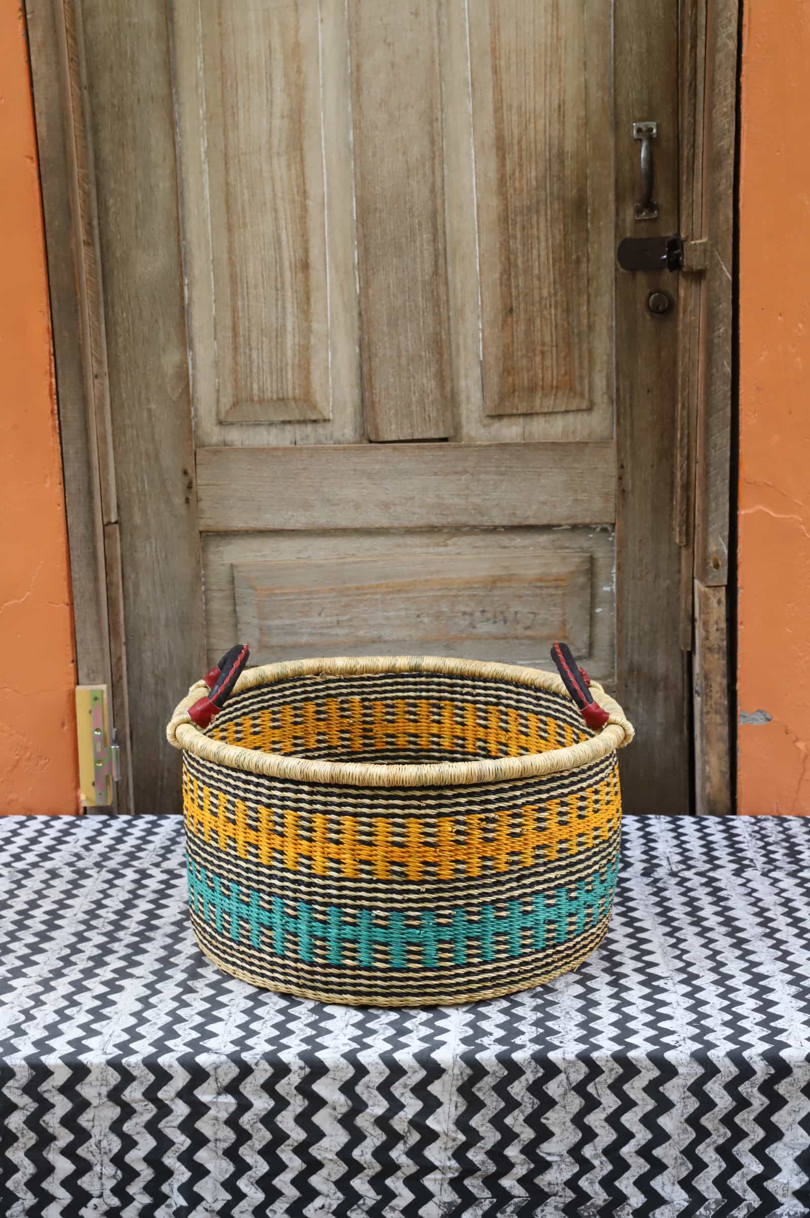 Woven Tub (Small) handwoven in Ghana sitting on black and white cloth with wooden door background


