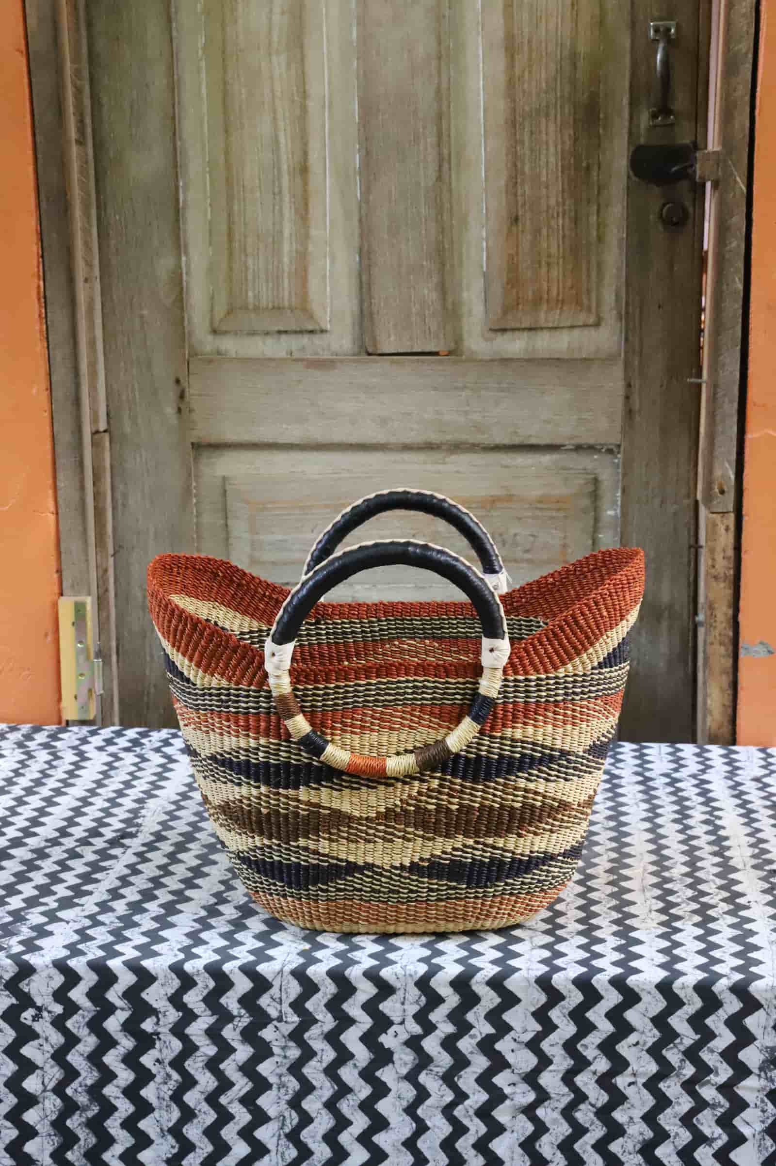Woven beach bag in terracotta, brown and natural diagonal stripes with circular leather handles