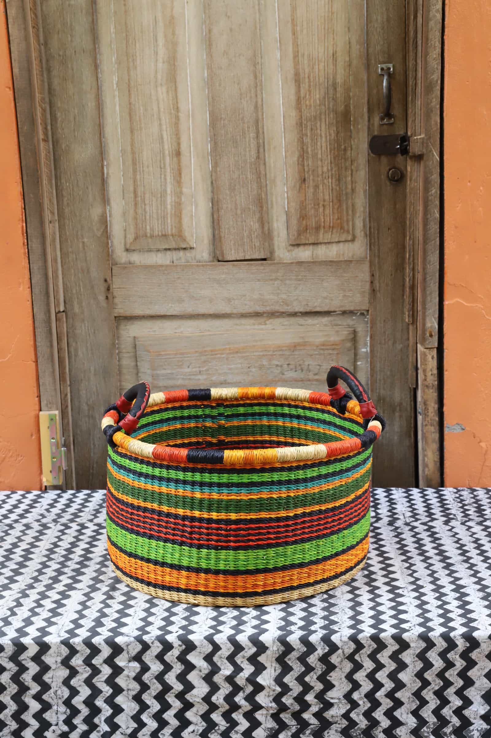 Woven Tub (Small) handwoven in Ghana sitting on black and white cloth with wooden door background