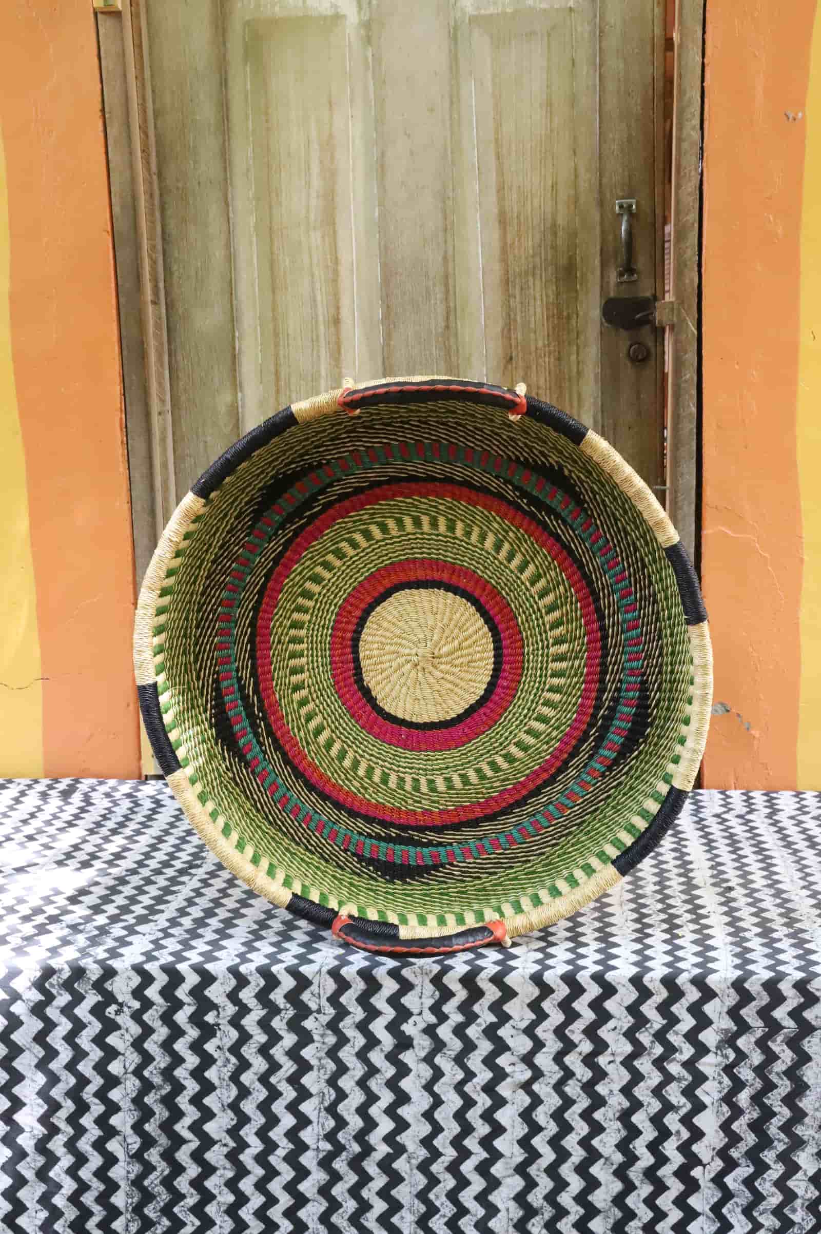 Medium double weave woven tray wall décor with concentric rings in green, magenta and black on chevron cloth.
