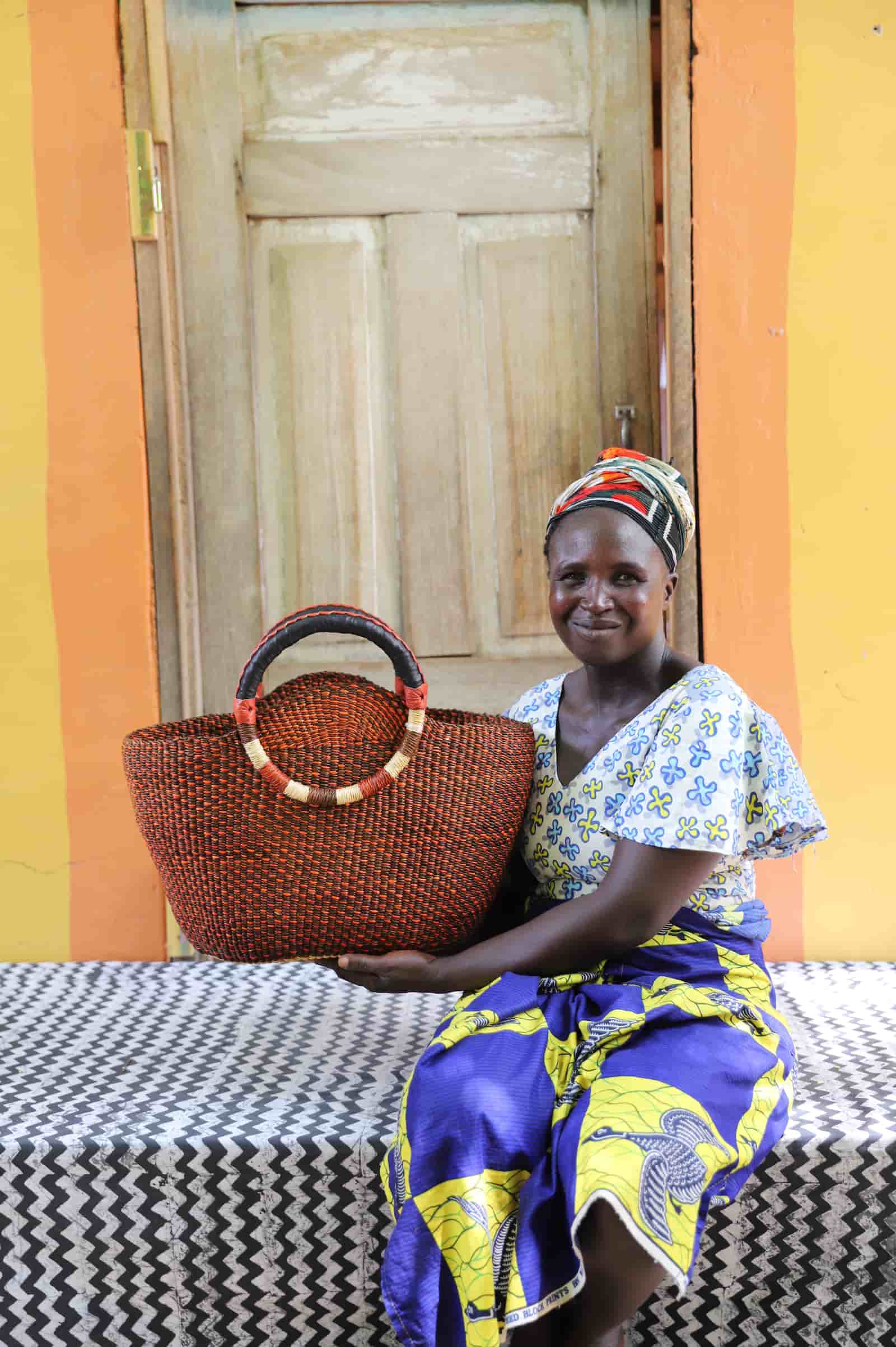 Woman holding Naughty George weekend bag in deep rust, showing scale and round handles