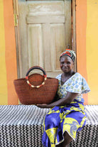 Woman holding Naughty George weekend bag in deep rust, showing scale and round handles