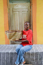 Woman holding large Pakurigo Wave Décor Basket in dark straw with amber, red and green check pattern