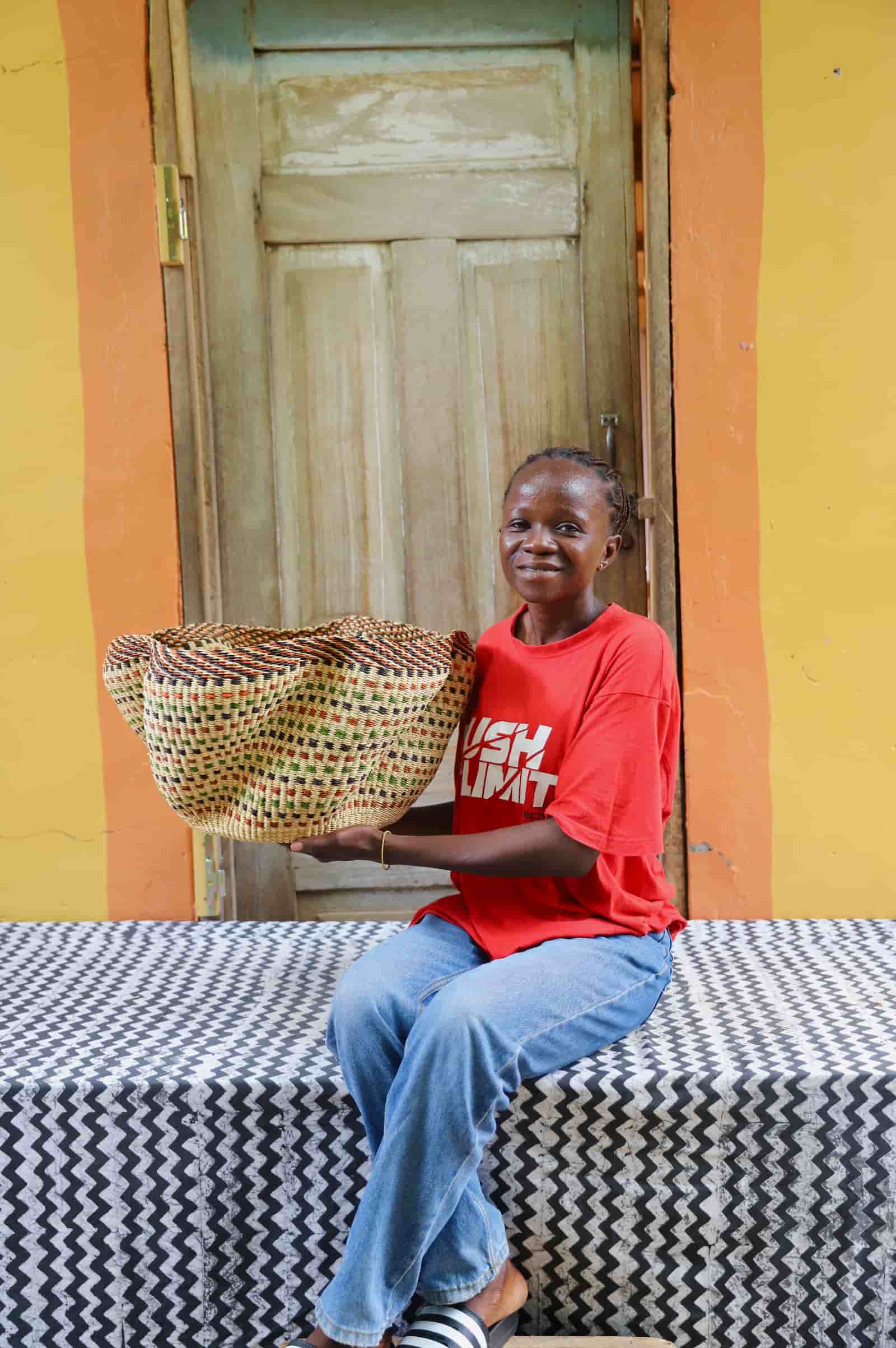 Woman holding large Pakurigo Wave Décor Basket in dark straw with amber, red and green check pattern