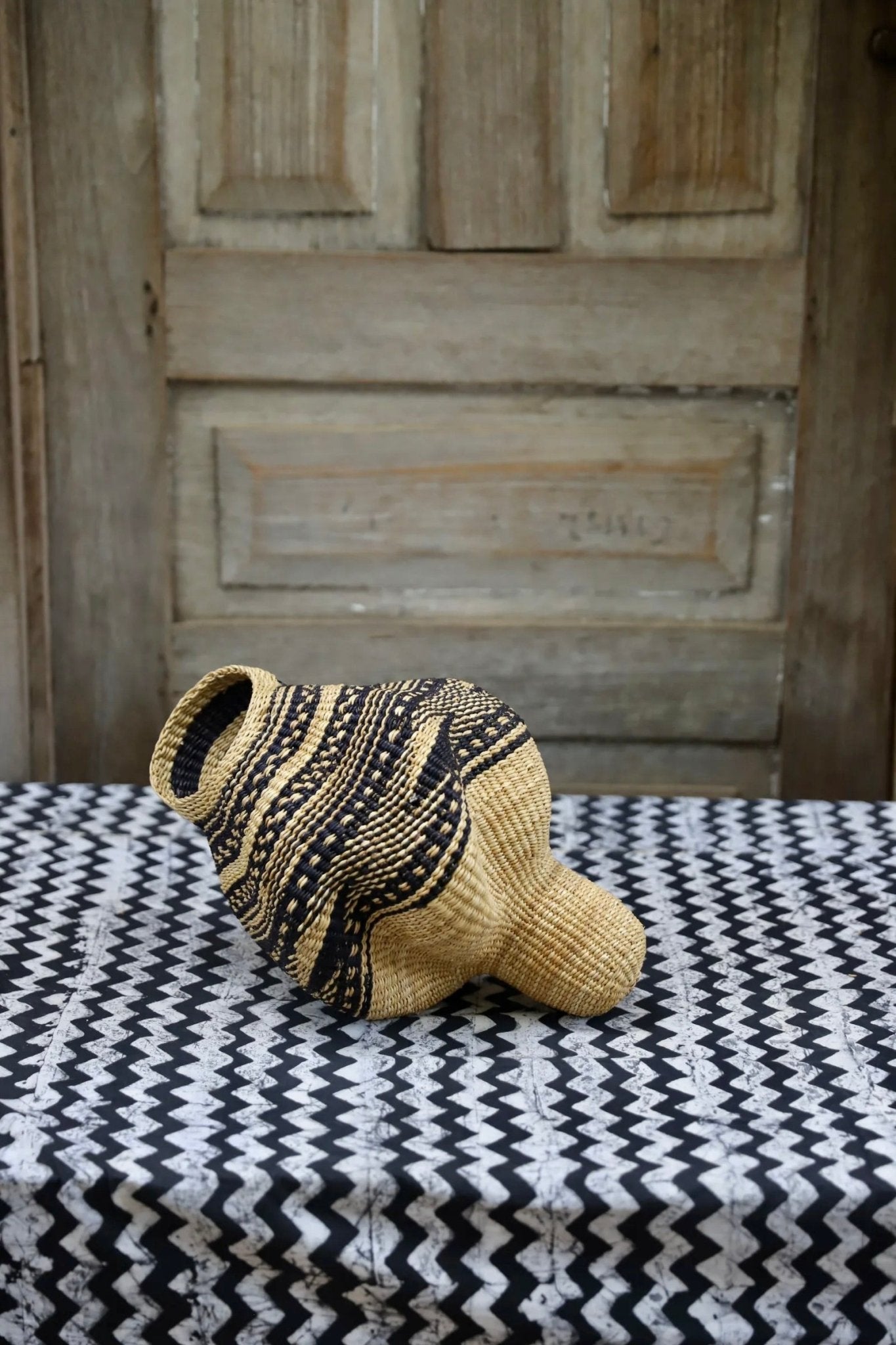 Patterned conch-shaped piece on a black and white cloth against a wooden door.