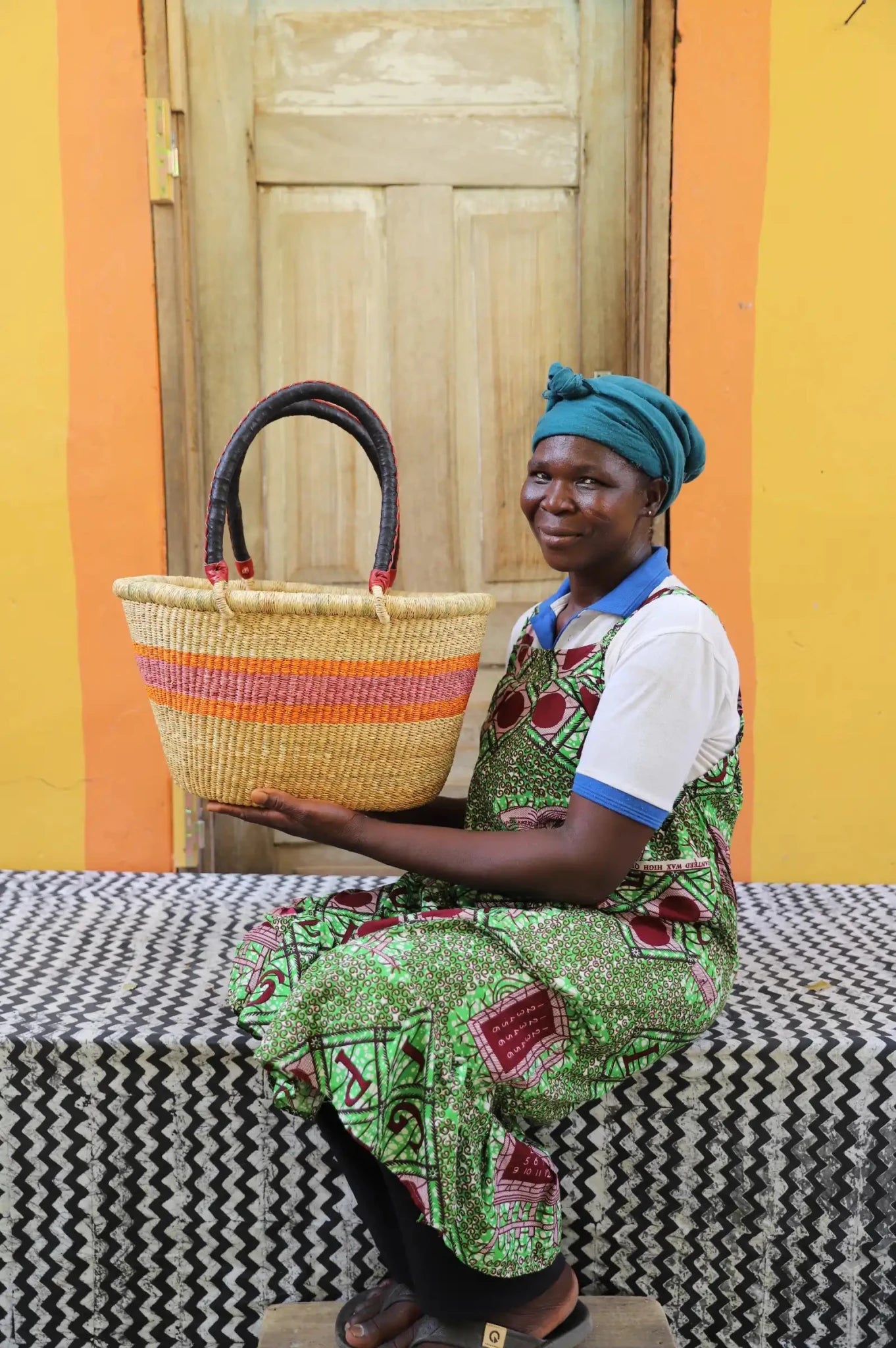 Woman holding medium Oval Shopping Basket in natural straw with orange stripe band, leather handles