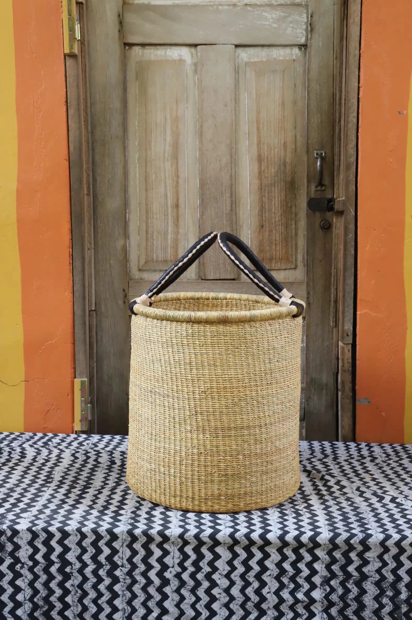 Open Laundry Basket (Medium) by The Baba Tree. Handwoven elephant grass storage with leather handles. Bolgatanga artisan decor.