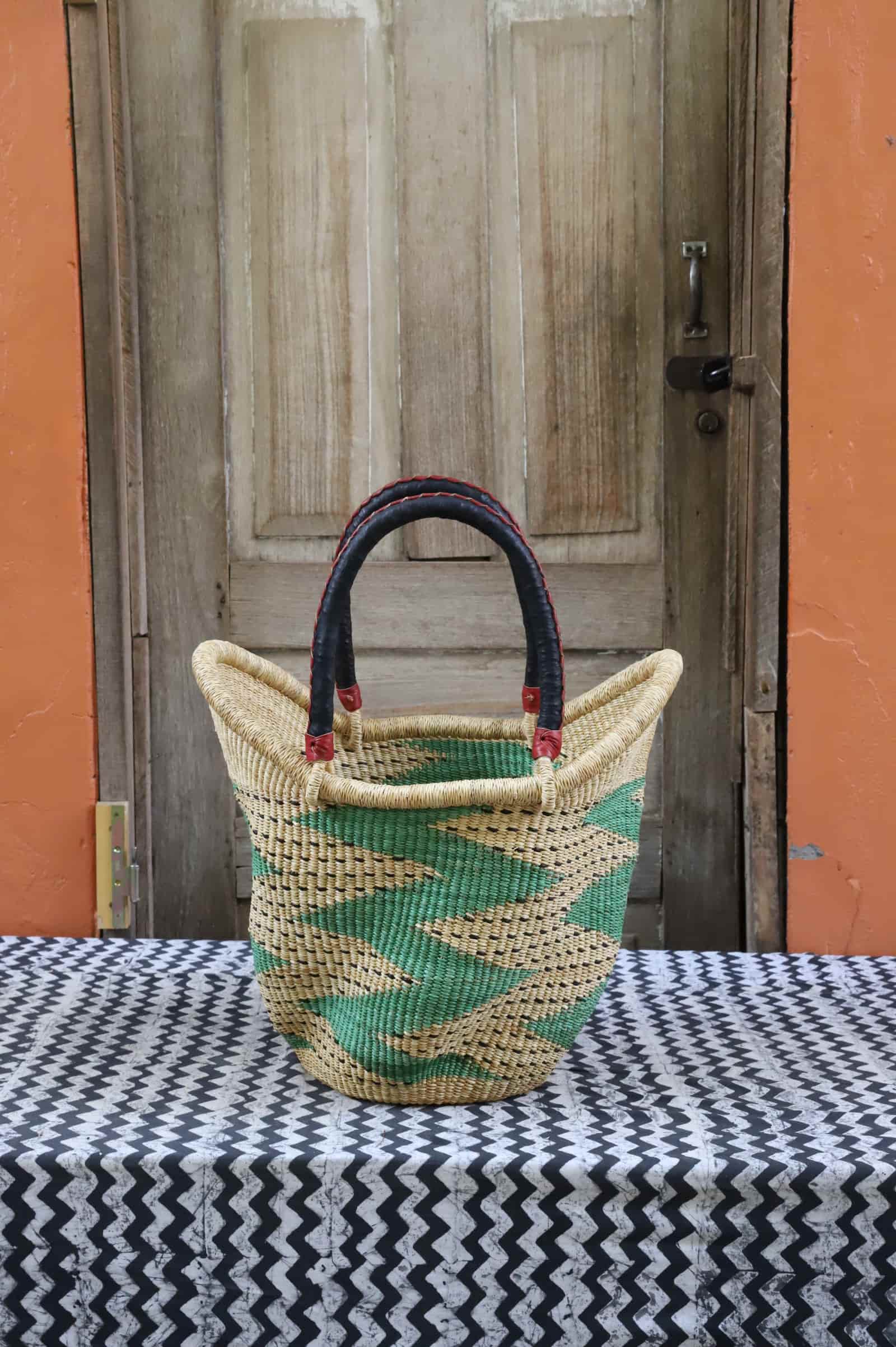 Woven carry on basket with premium leather on a black and white cloth against a wooden door