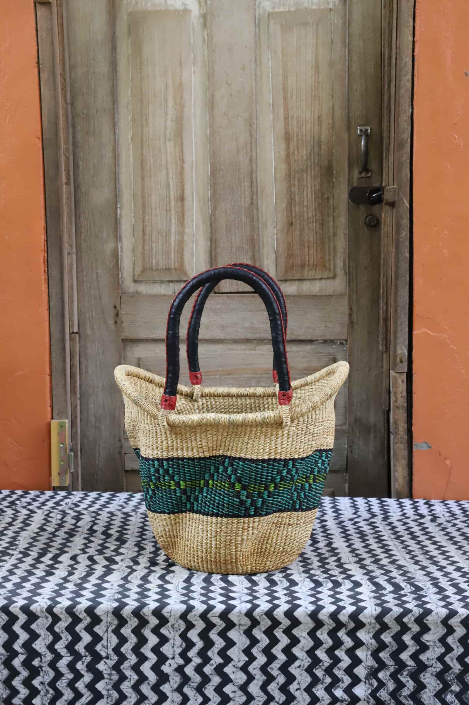 Woven carry on basket with premium leather on a black and white cloth against a wooden door