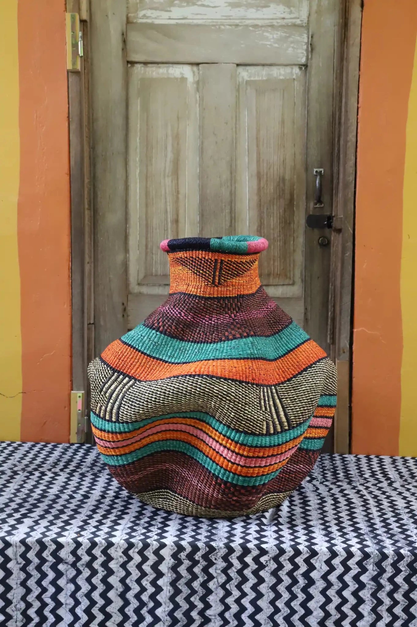Colorful woven basket on a table with a wooden door and colorful wall in the background