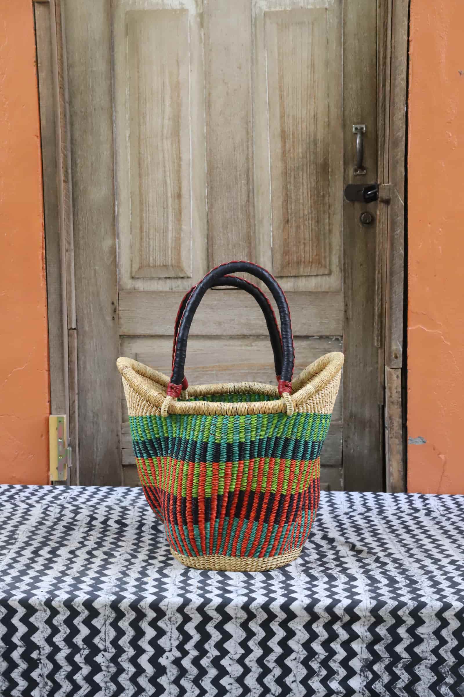 Woven carry on basket with premium leather on a black and white cloth against a wooden door